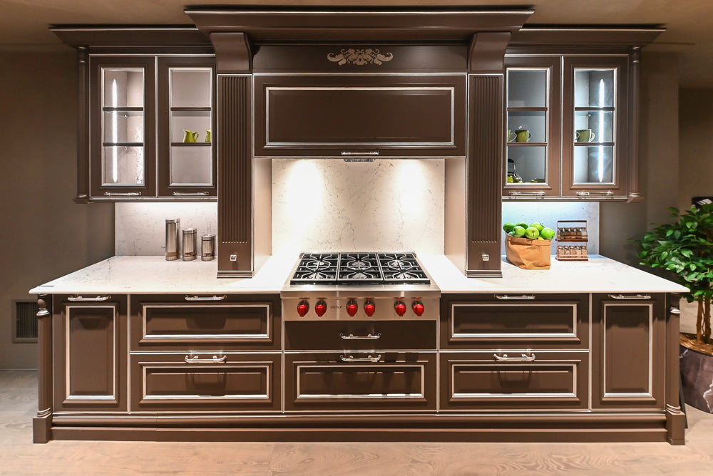 Dark brown showroom display kitchen with premium cabinetry, central range and marble countertops