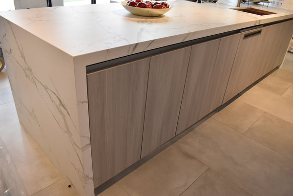 Sustainable kitchen island with wood-effect cabinetry and a white marble waterfall countertop.