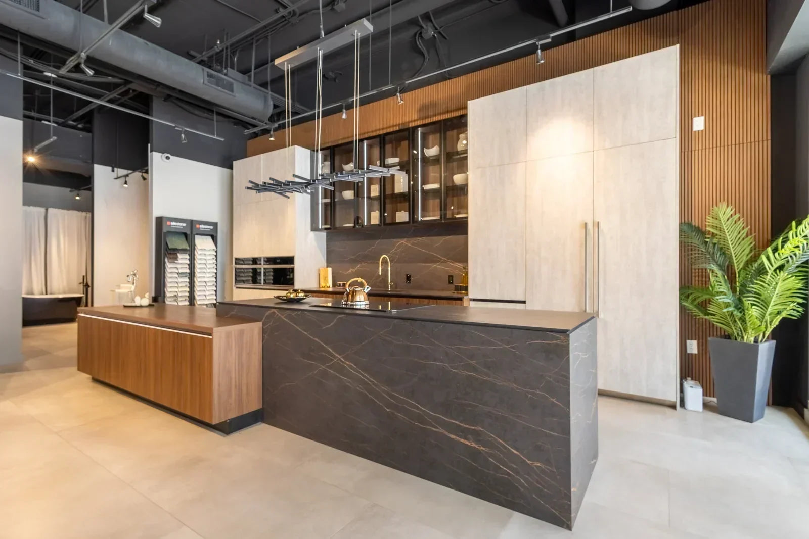 Modern kitchen showrooms displaying a luxury kitchen with a dark stone island, wood cabinetry and premium integrated appliances.