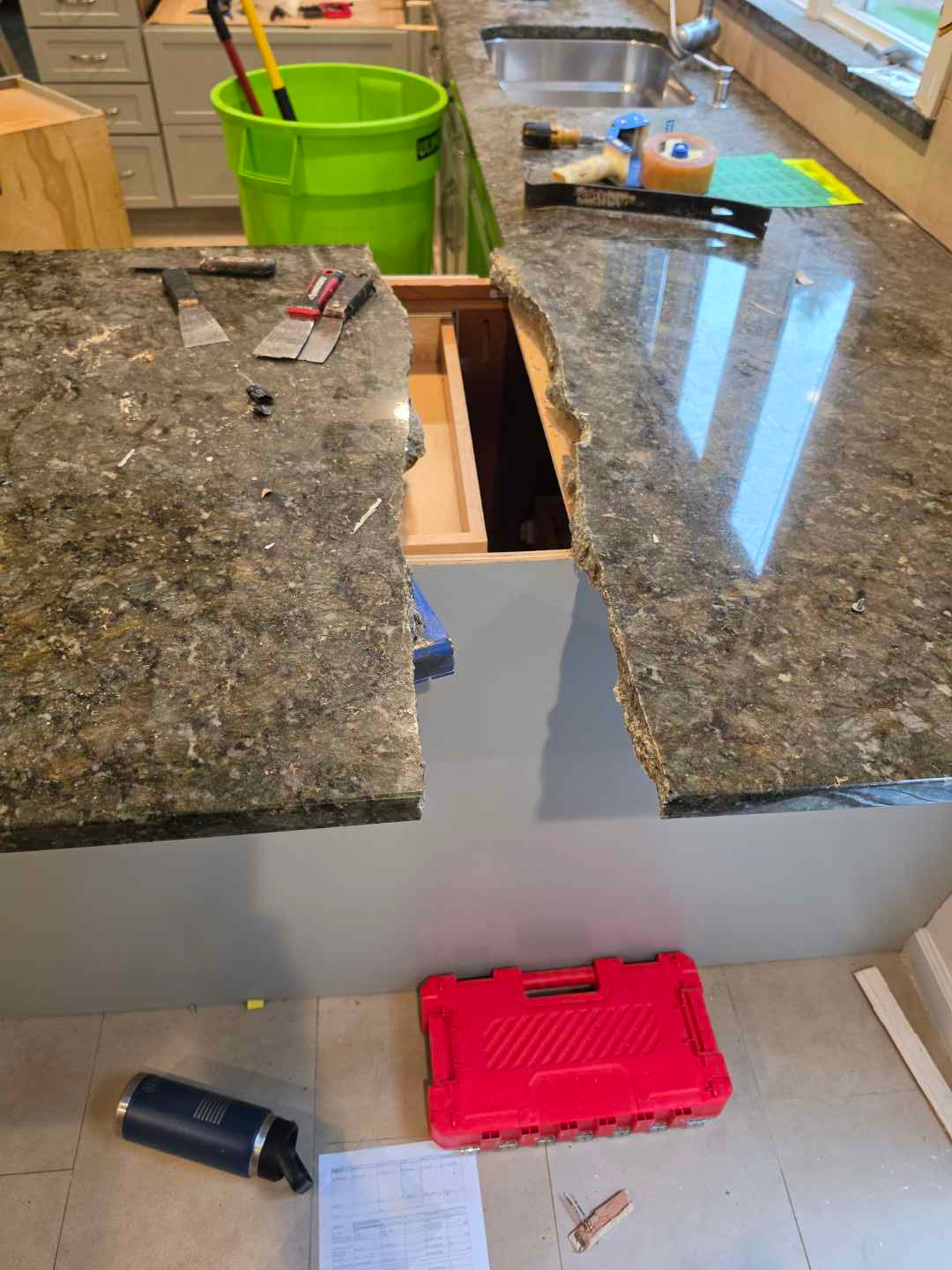 Aurora Circ kitchen renovation with dark granite countertops separated for removal and tools beside exposed cabinet bases