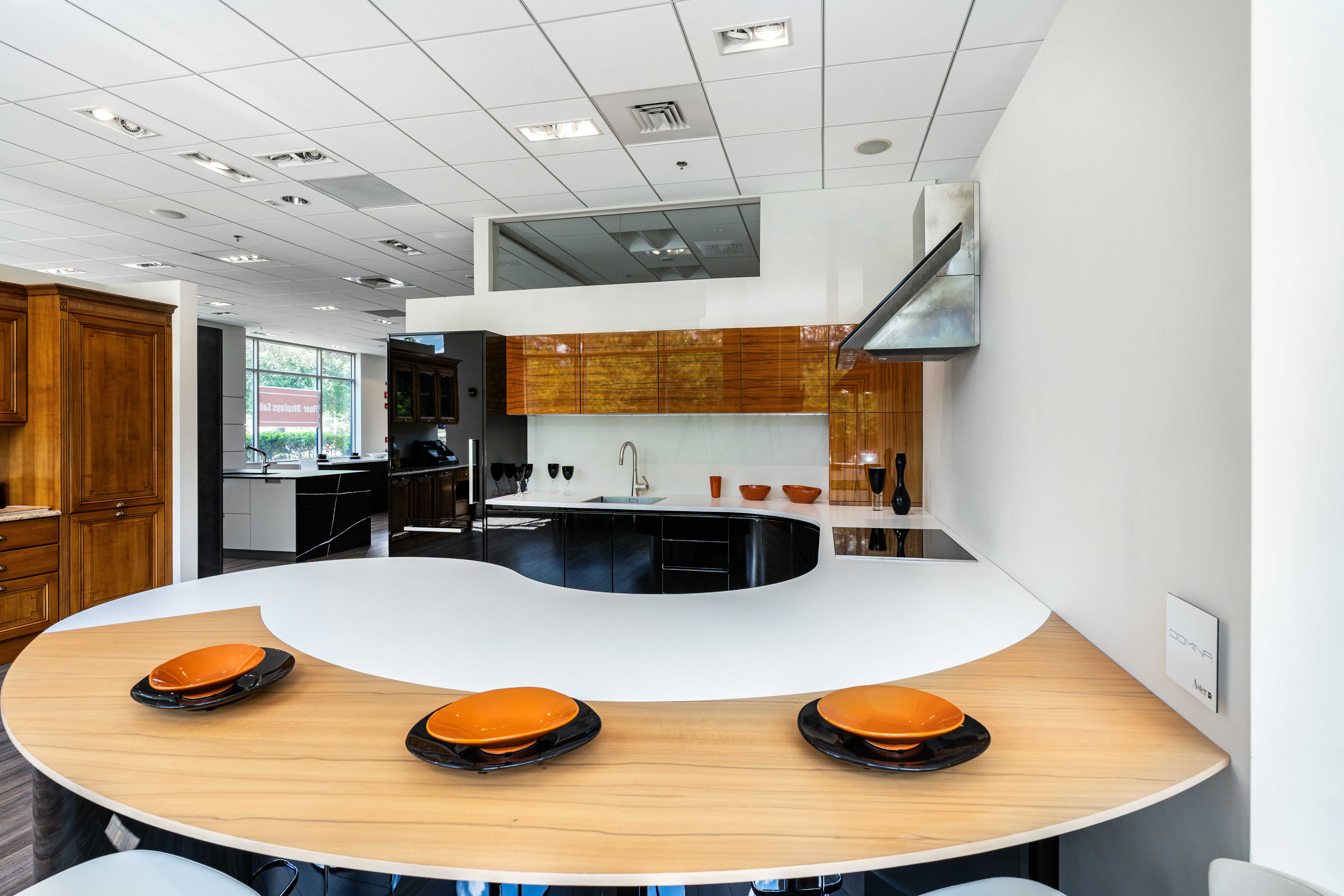 The Aster Curved Luxe Aster Cucine modern glossy black curvy kitchen cabinetry with large central island and Miele appliances front view