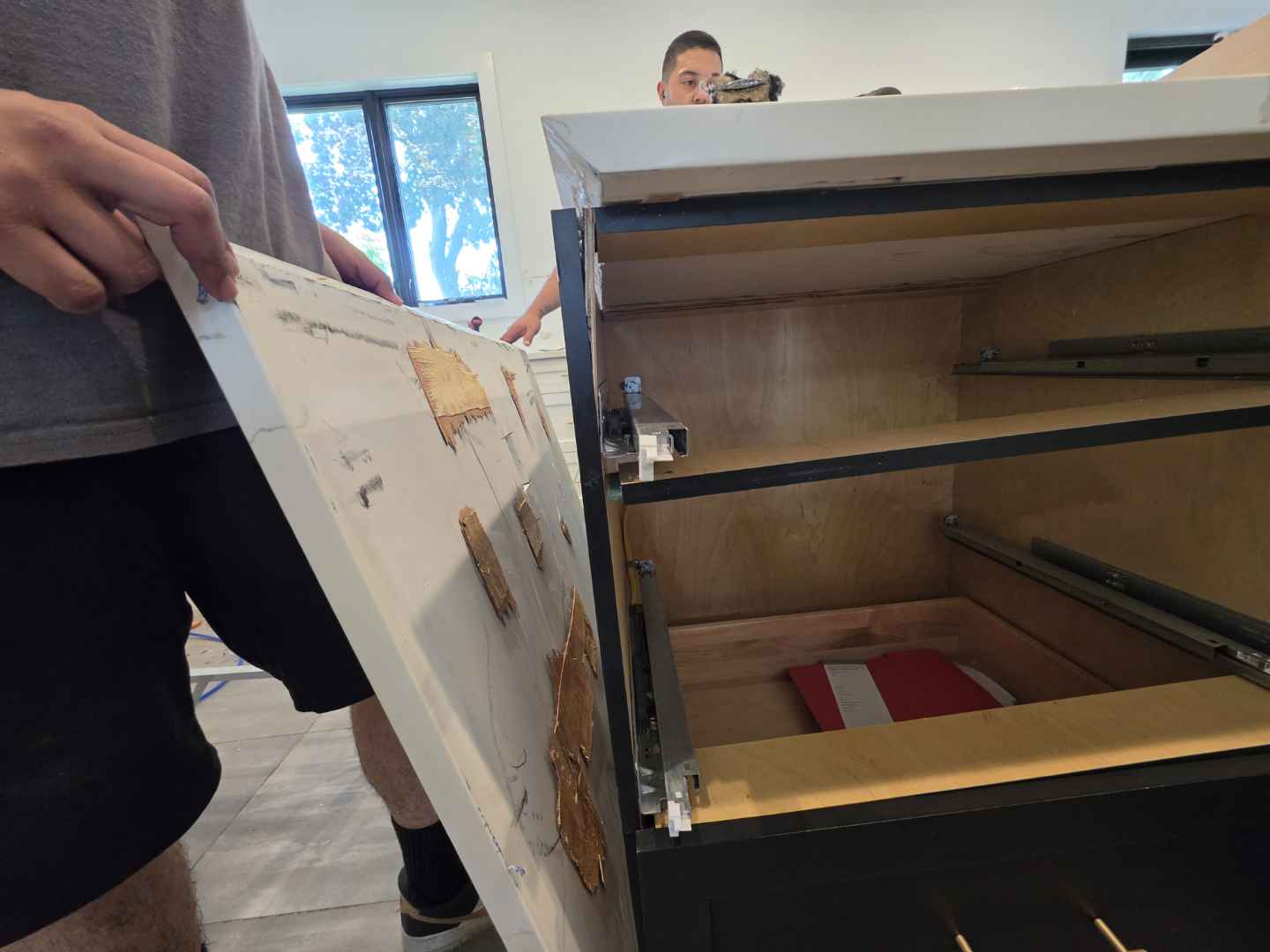 Aurora Circ dark kitchen cabinet with warm wood interior and exposed drawer hardware during showroom installation