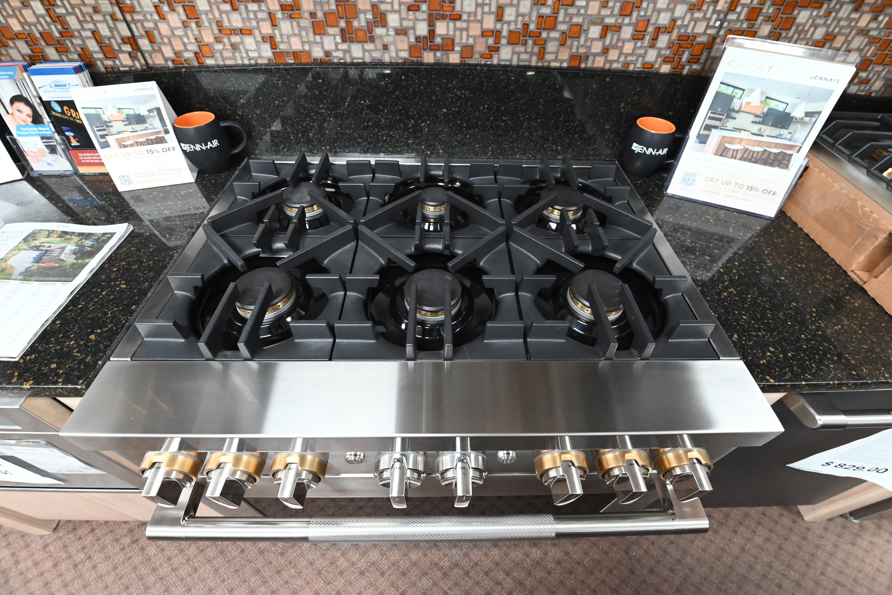 Luxury professional 36 inch dual fuel range cooktop showing six brass burners and continuous cast iron grates