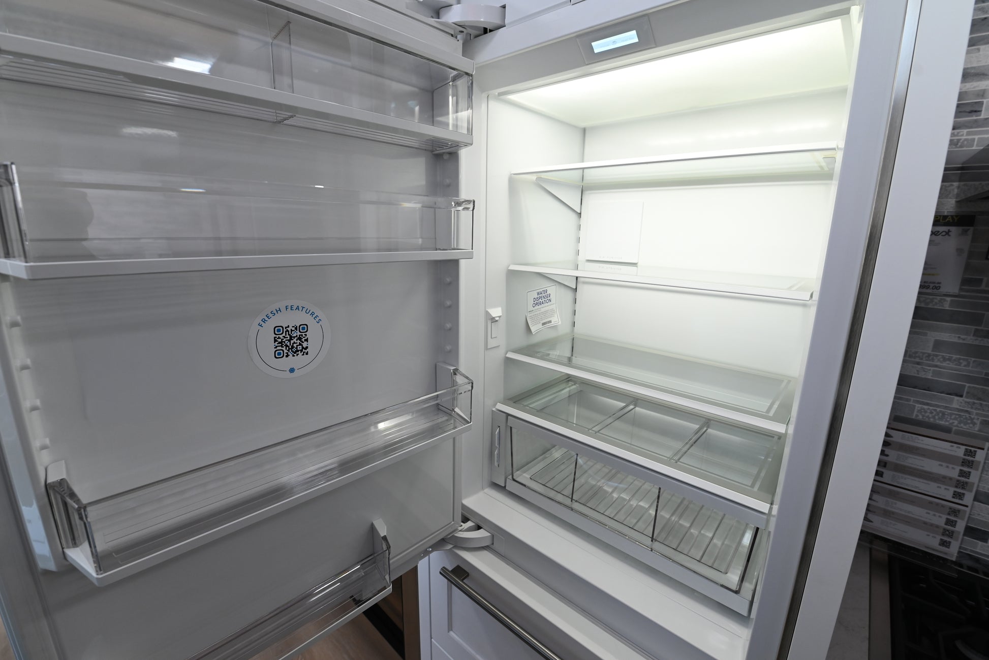 Luxury 30 inch integrated refrigerator showing open doors holding fresh food and internal water dispenser