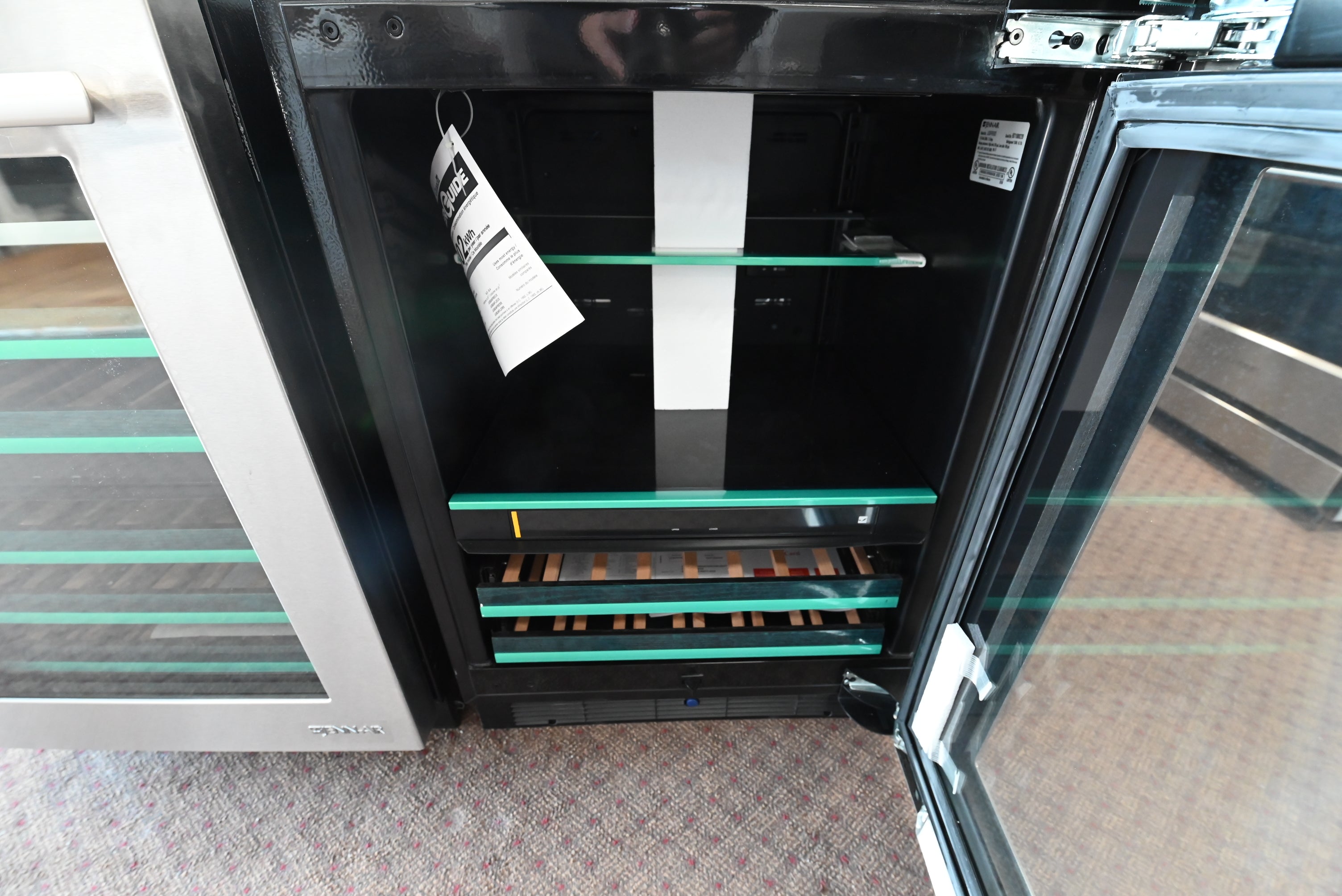 Open glass door of a 24 inch premium JennAir beverage center showing beechwood wine tines and illuminated interior shelves