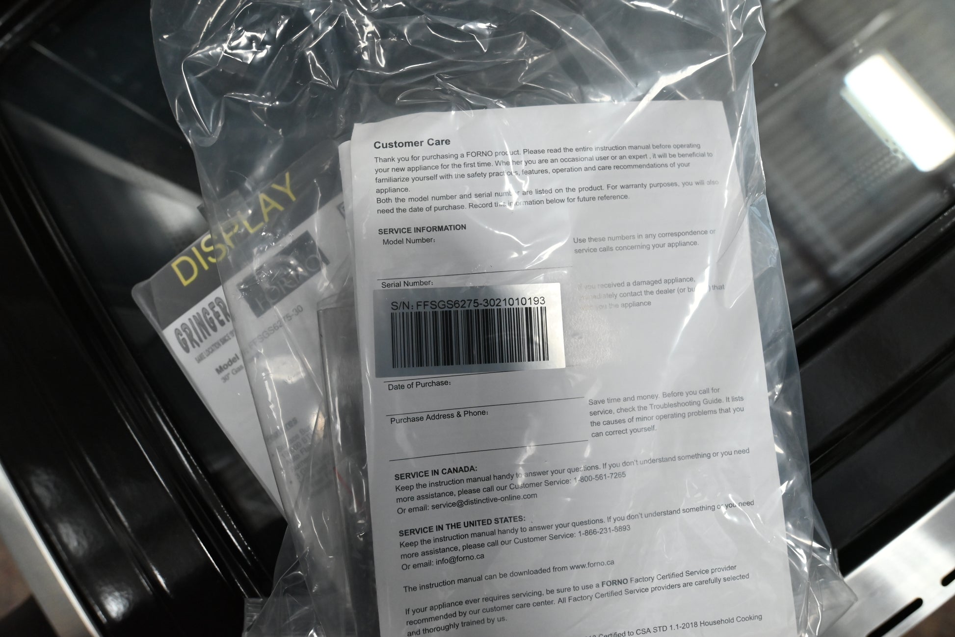 A clear plastic protective sleeve containing a white paper insert with printed customer care text, a barcode, and return information, photographed inside a dark retail display case.