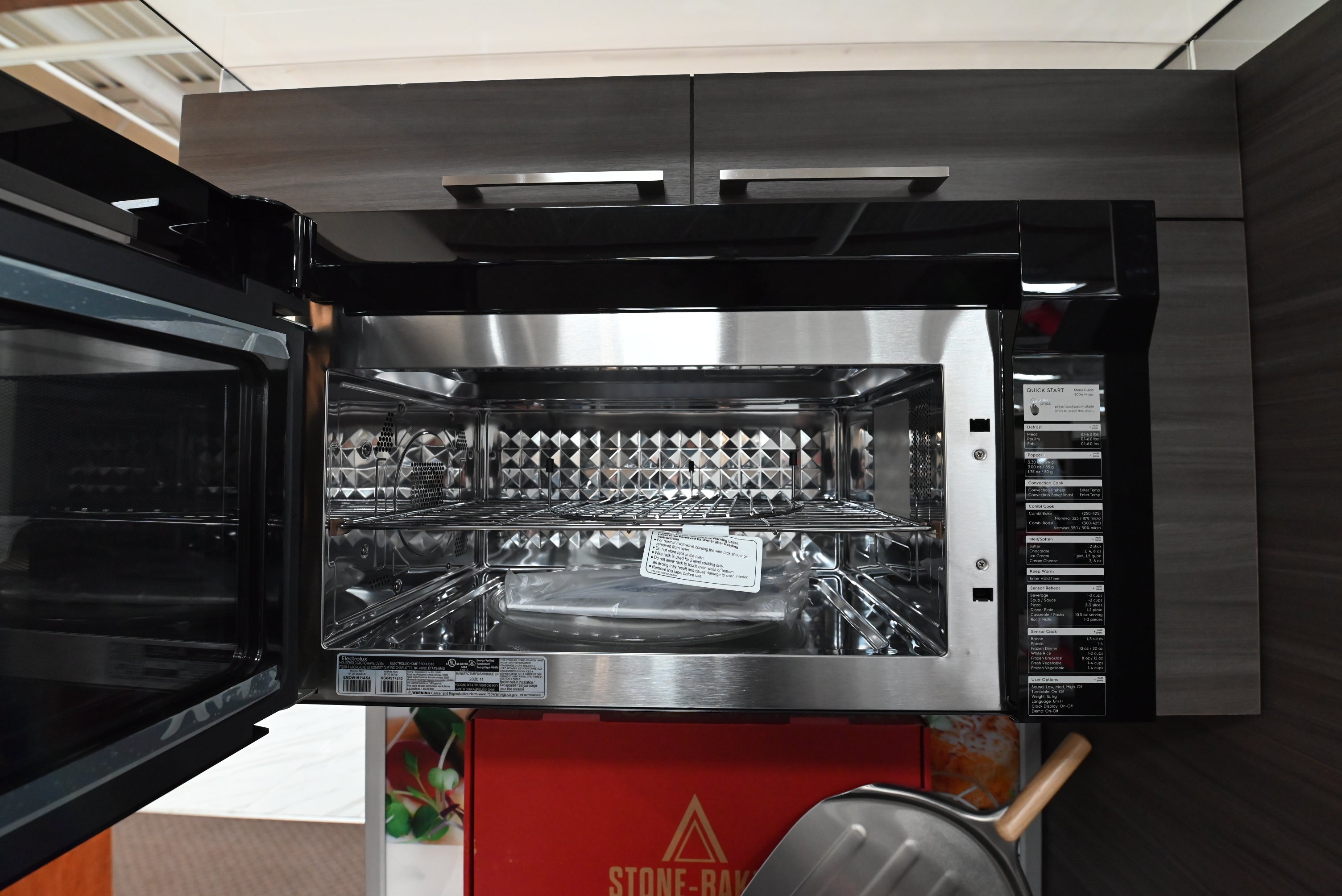 Underneath view of Electrolux EMOW1911AS microwave highlighting dual grease filters and bright LED stove lighting