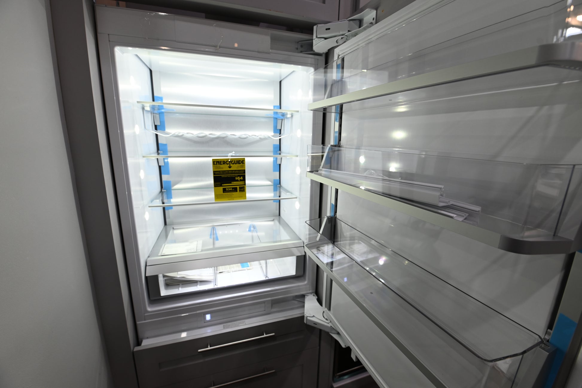 Interior view of the illuminated glass shelving and dual evaporator storage zones of a Monogram ZIC303NPPII integrated refrigerator