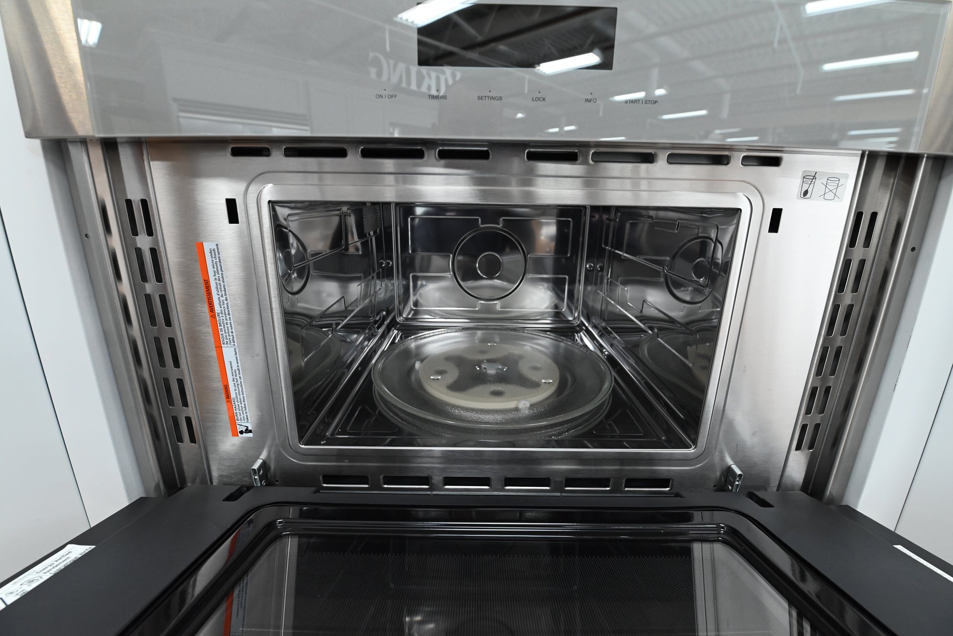 Luxury 30 inch wall microwave open downward showing stainless steel interior and wire shelf