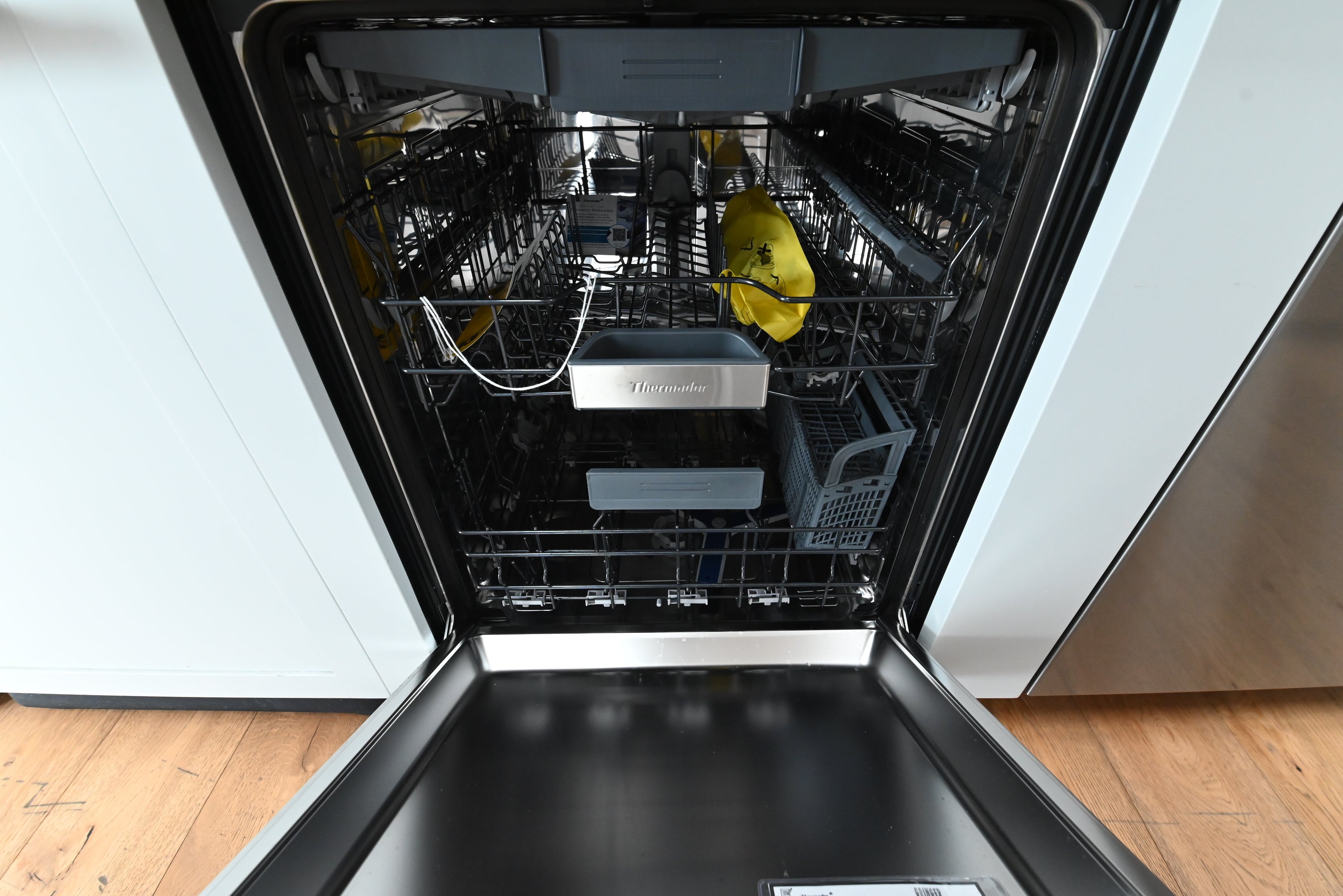 Luxury 24 inch integrated dishwasher open showing full stainless steel tub and blue Sapphire Glow lighting