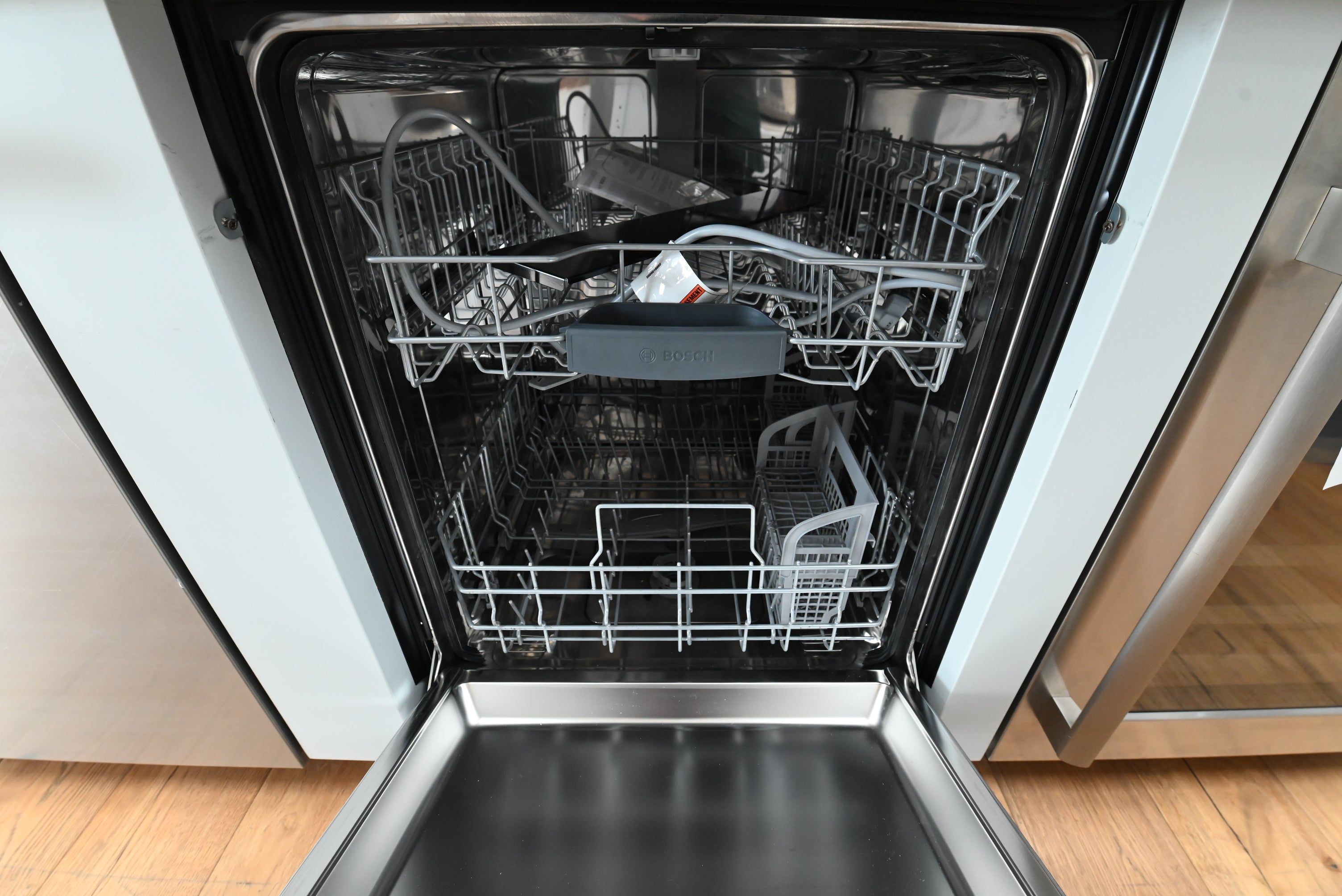Luxury 24 inch built in dishwasher open showing internal racks and stainless steel interior