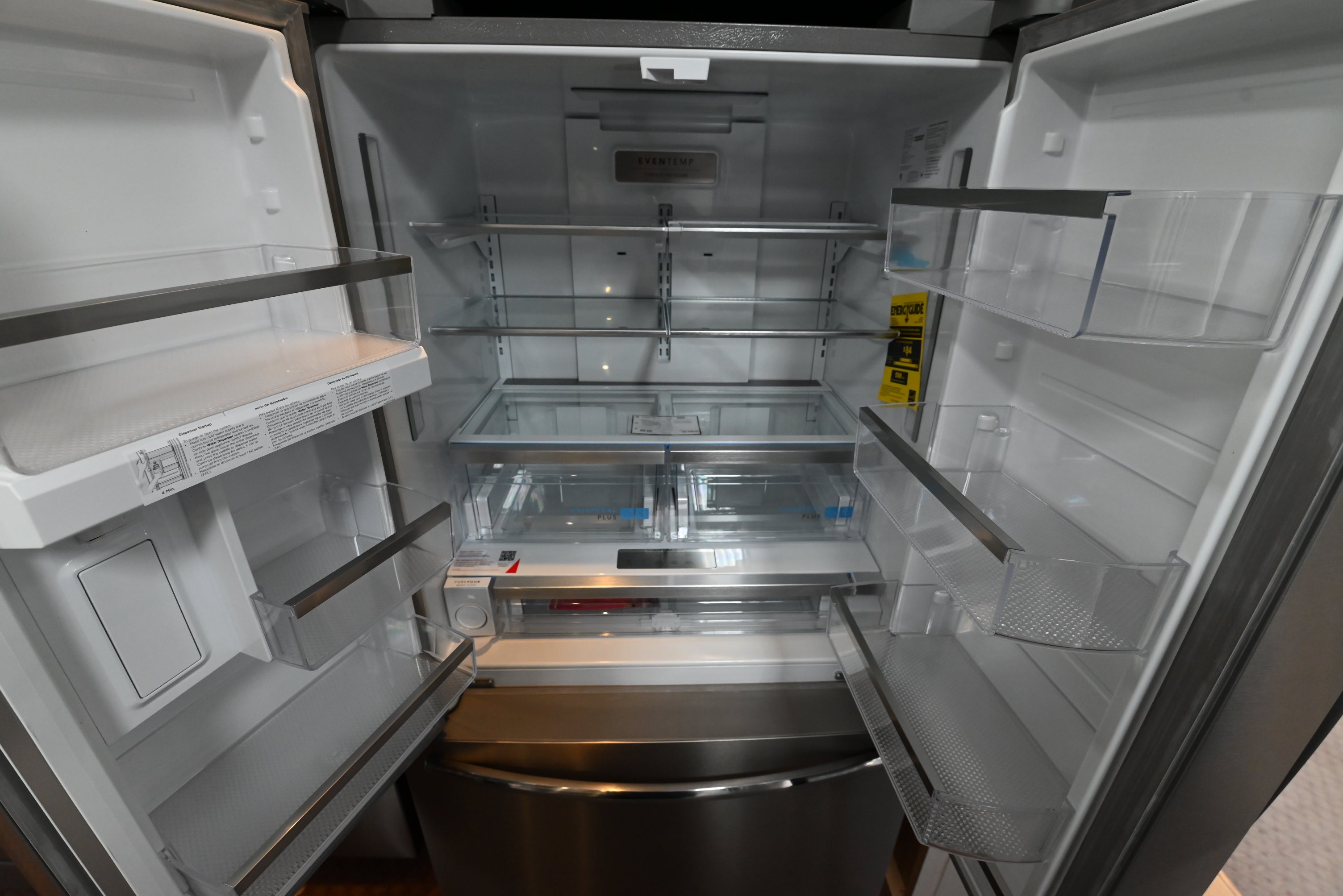 Luxury counter depth french door refrigerator open showing wide LED lit shelving and fresh crisper drawers