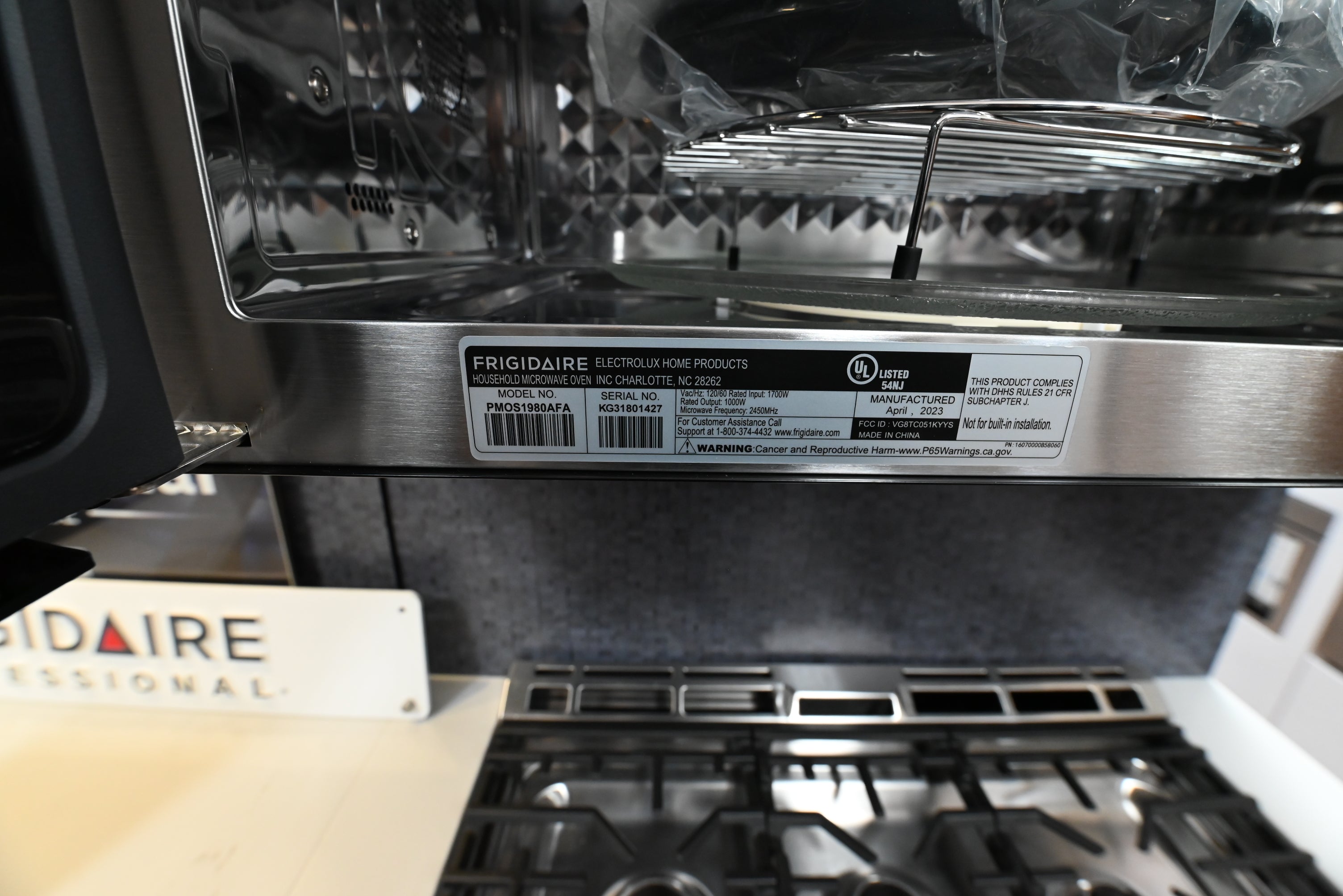 Frigidaire Pro over the range microwave mounted flush beneath modern white cabinets above a gas range