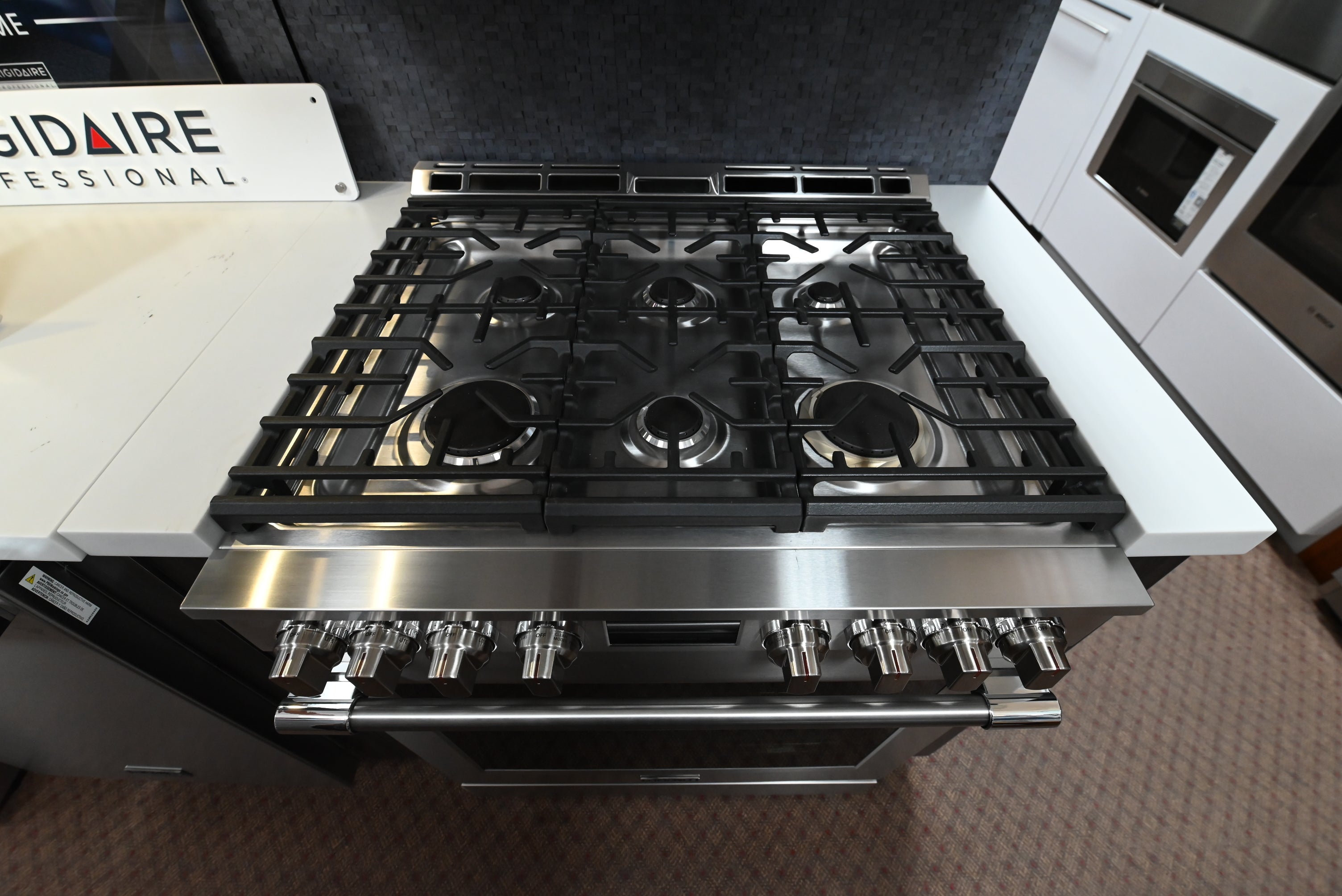 Luxury 30 inch slide in gas cooktop showing six burners continuous cast iron grates and integrated griddle pan