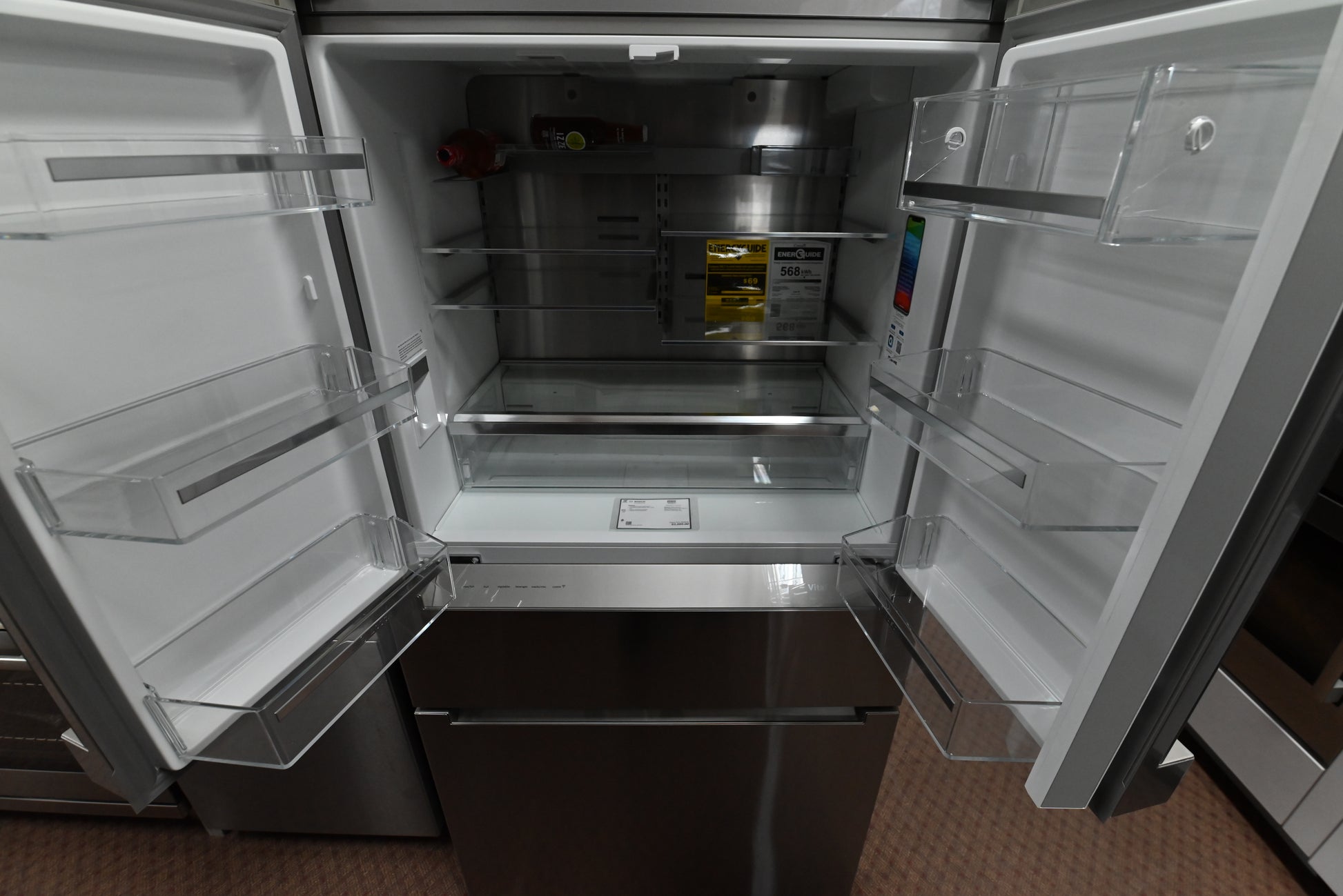 Luxury 4 door freestanding refrigerator open showing stainless steel backwall and FlexBar shelf