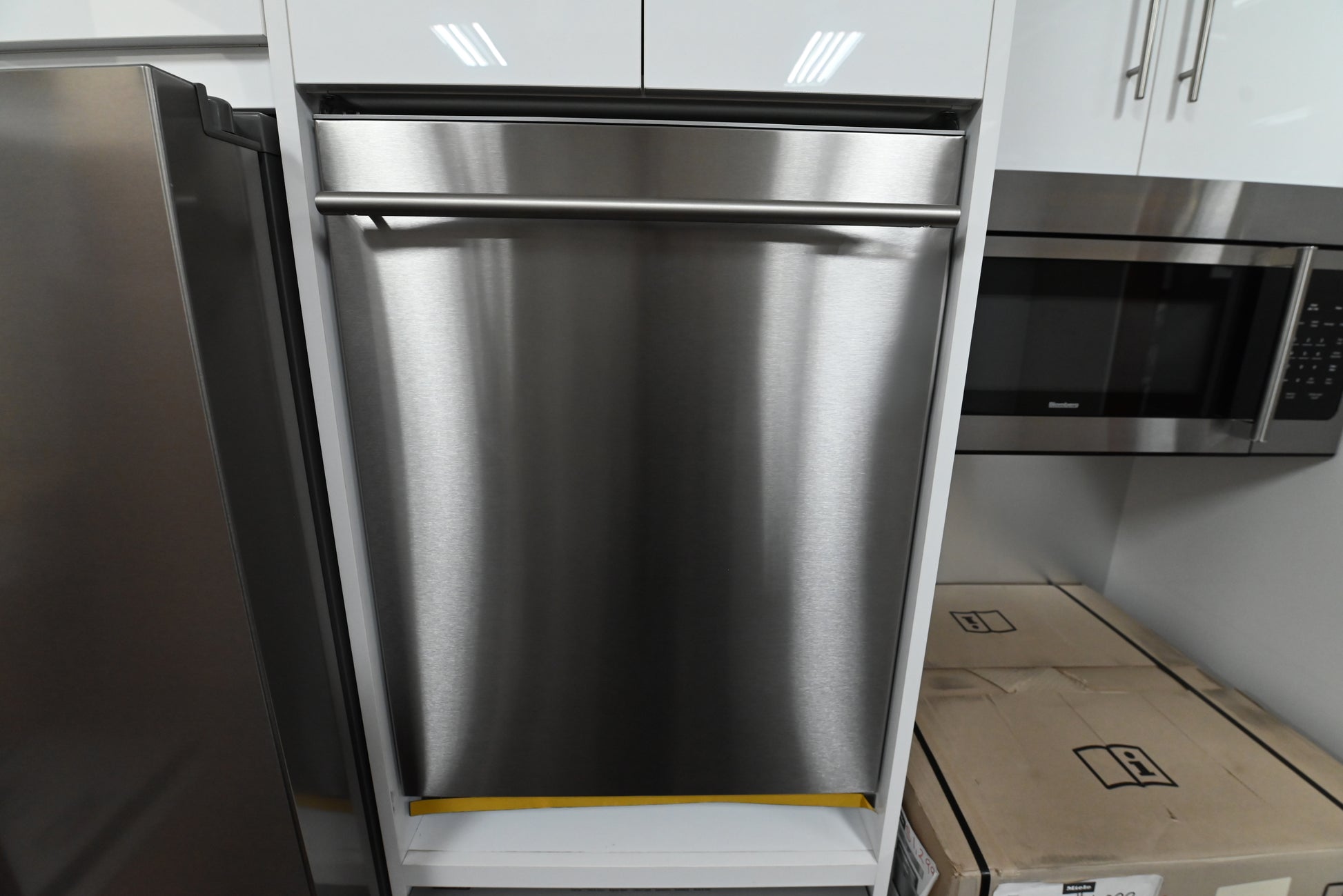 Luxury 24 inch dishwasher open showing bright LED interior illumination three tiers of racks and full stainless steel tub