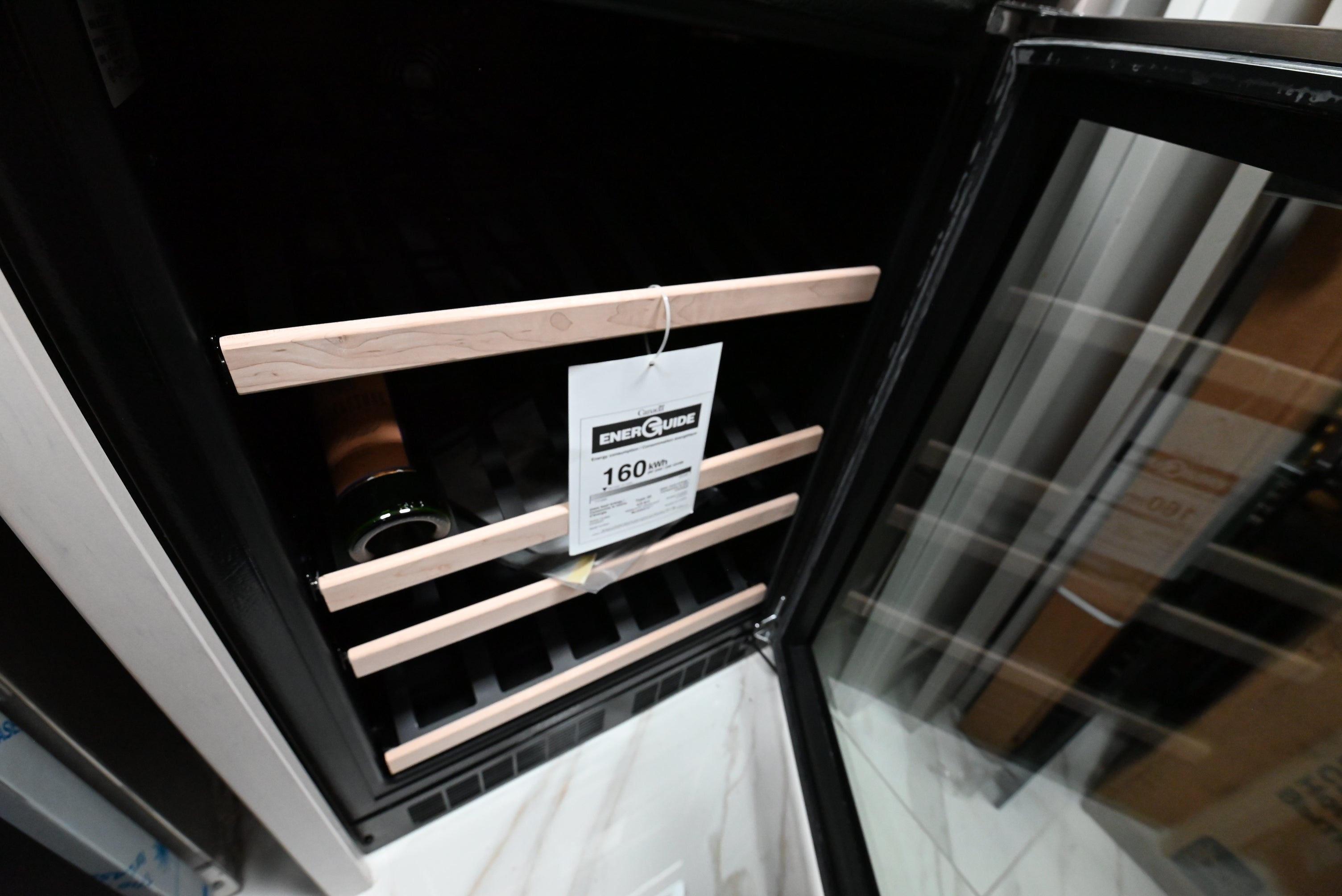 Luxury under counter wine refrigerator open showing 27 bottle capacity maple wood trim shelves and white LED lighting