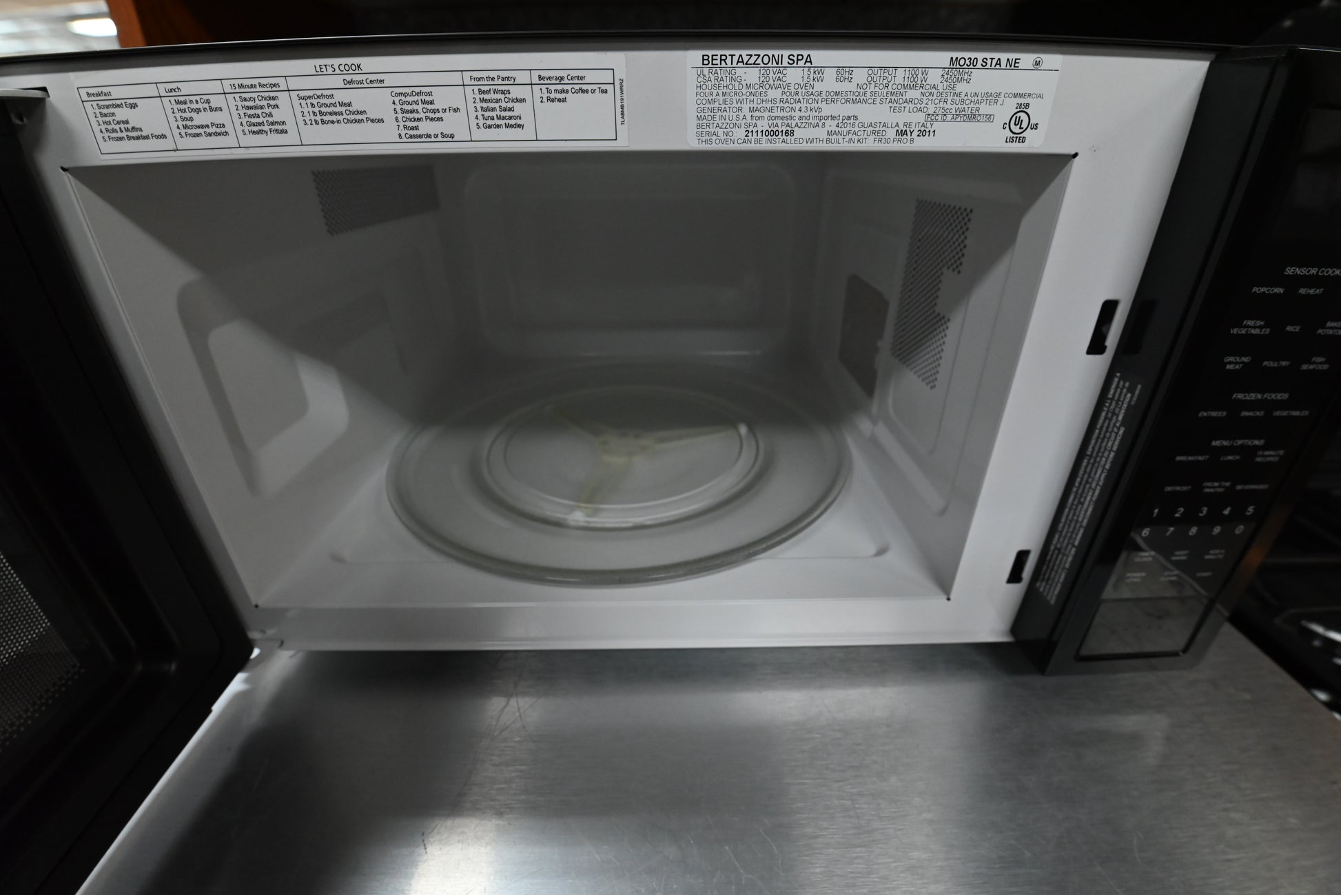 Luxury 24 inch black microwave door open showing white enameled cavity and 16 inch glass turntable