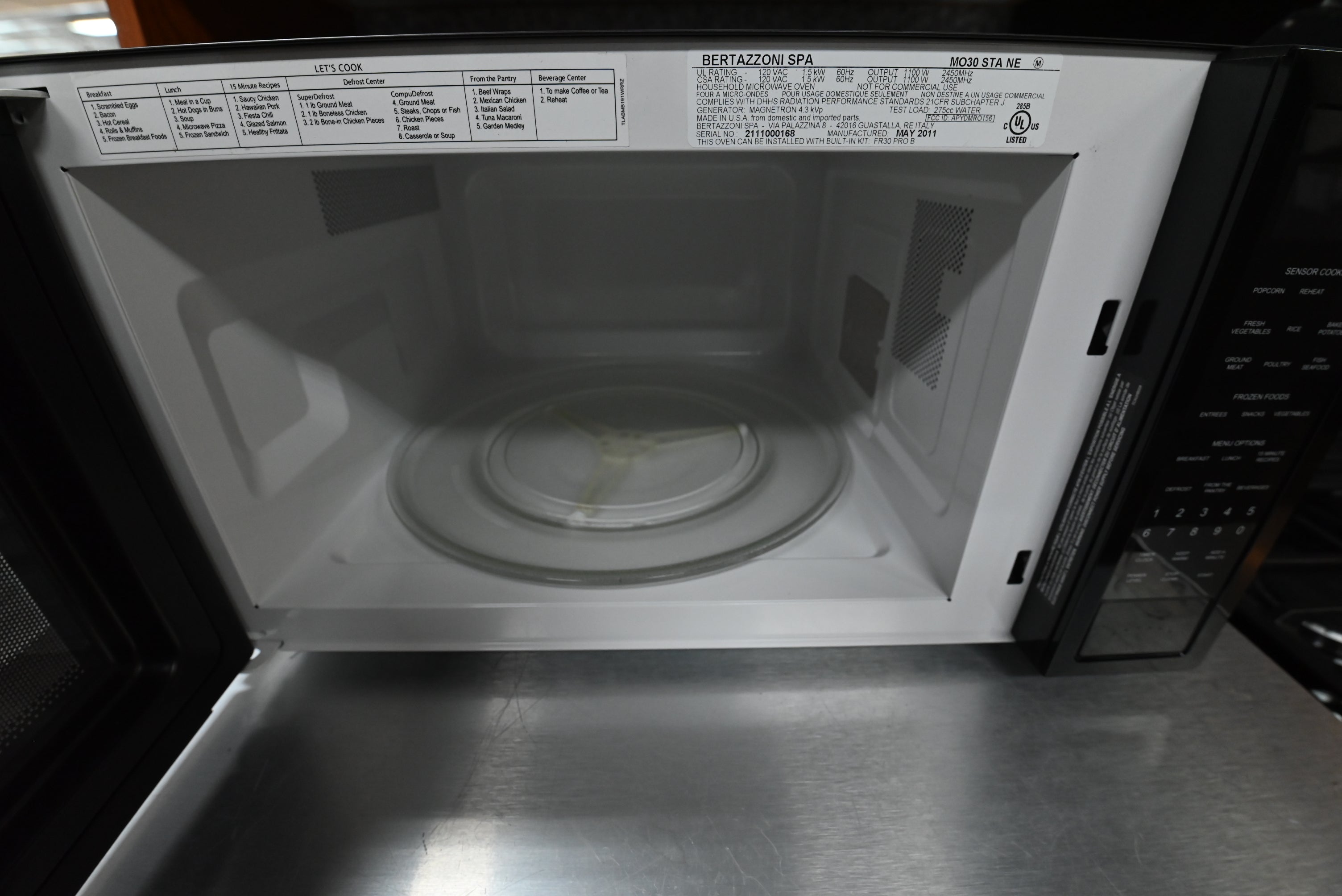 Luxury 24 inch black microwave door open showing white enameled cavity and 16 inch glass turntable