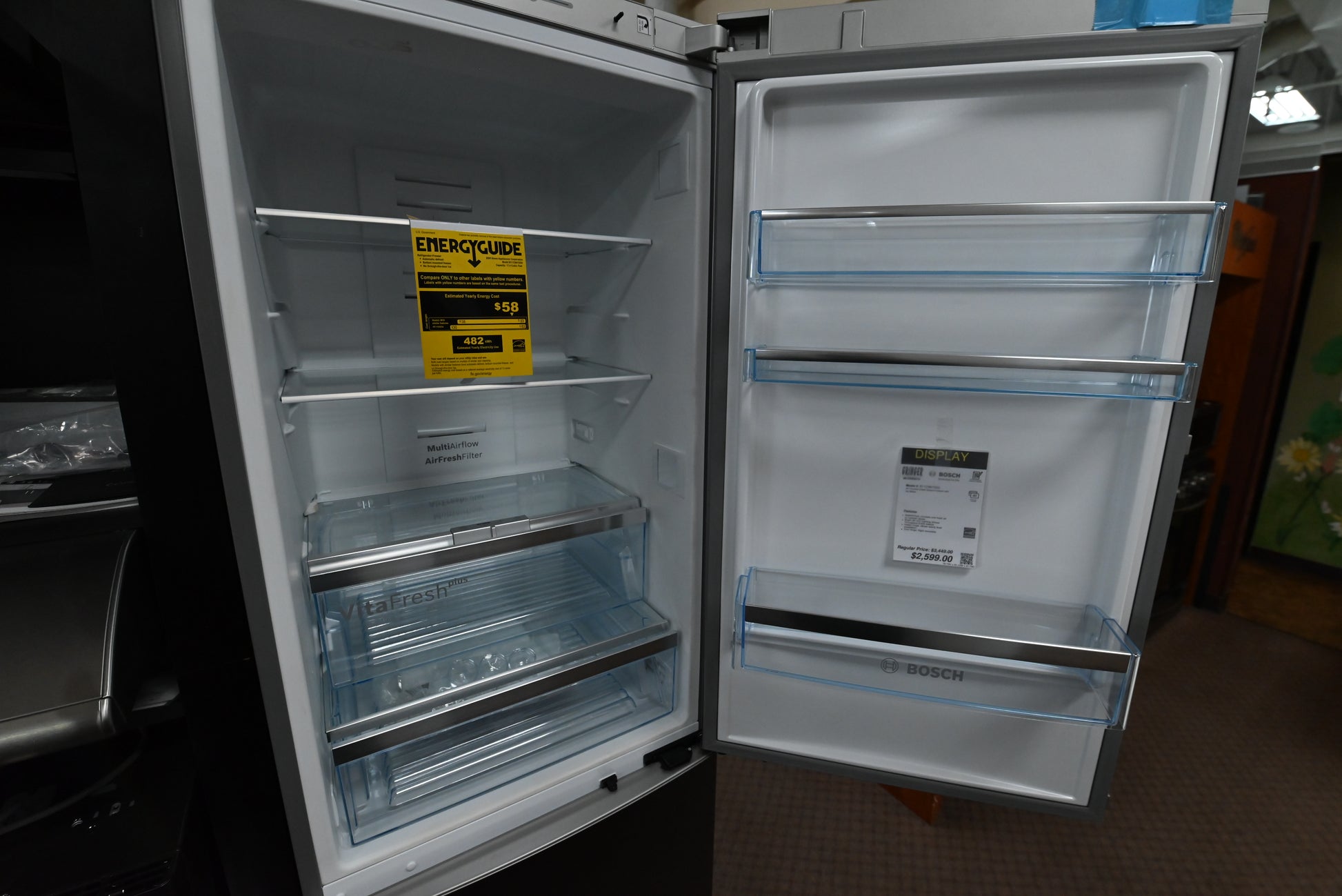 Luxury 24 inch slim freestanding refrigerator open showing glass shelves and chrome wine rack
