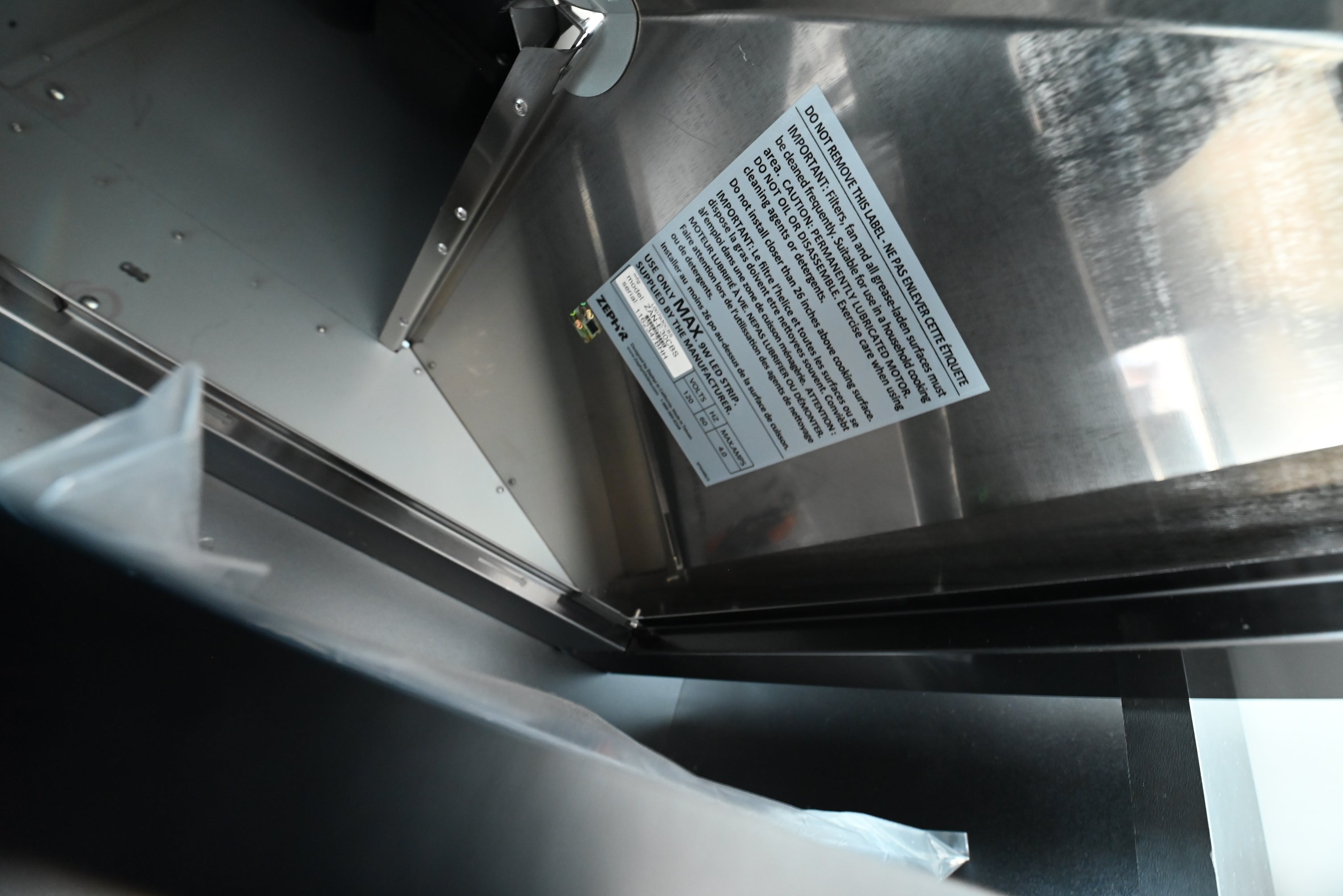 Black stainless steel chimney range hood looking up showing aluminum mesh filters and BriteStrip LED lighting