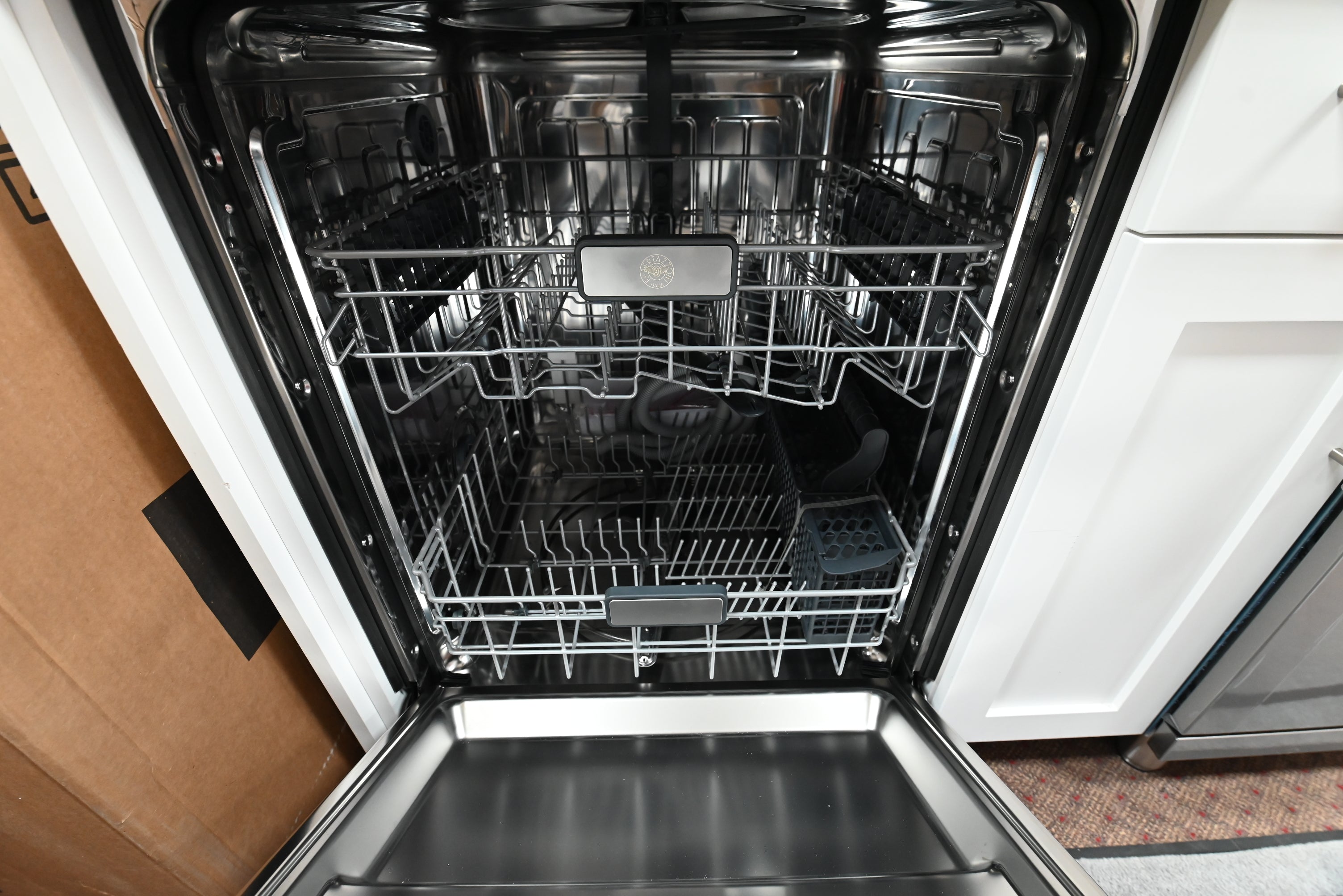 Luxury 24 inch Bertazzoni integrated dishwasher door open showing stainless steel tub three spray arms and two racks