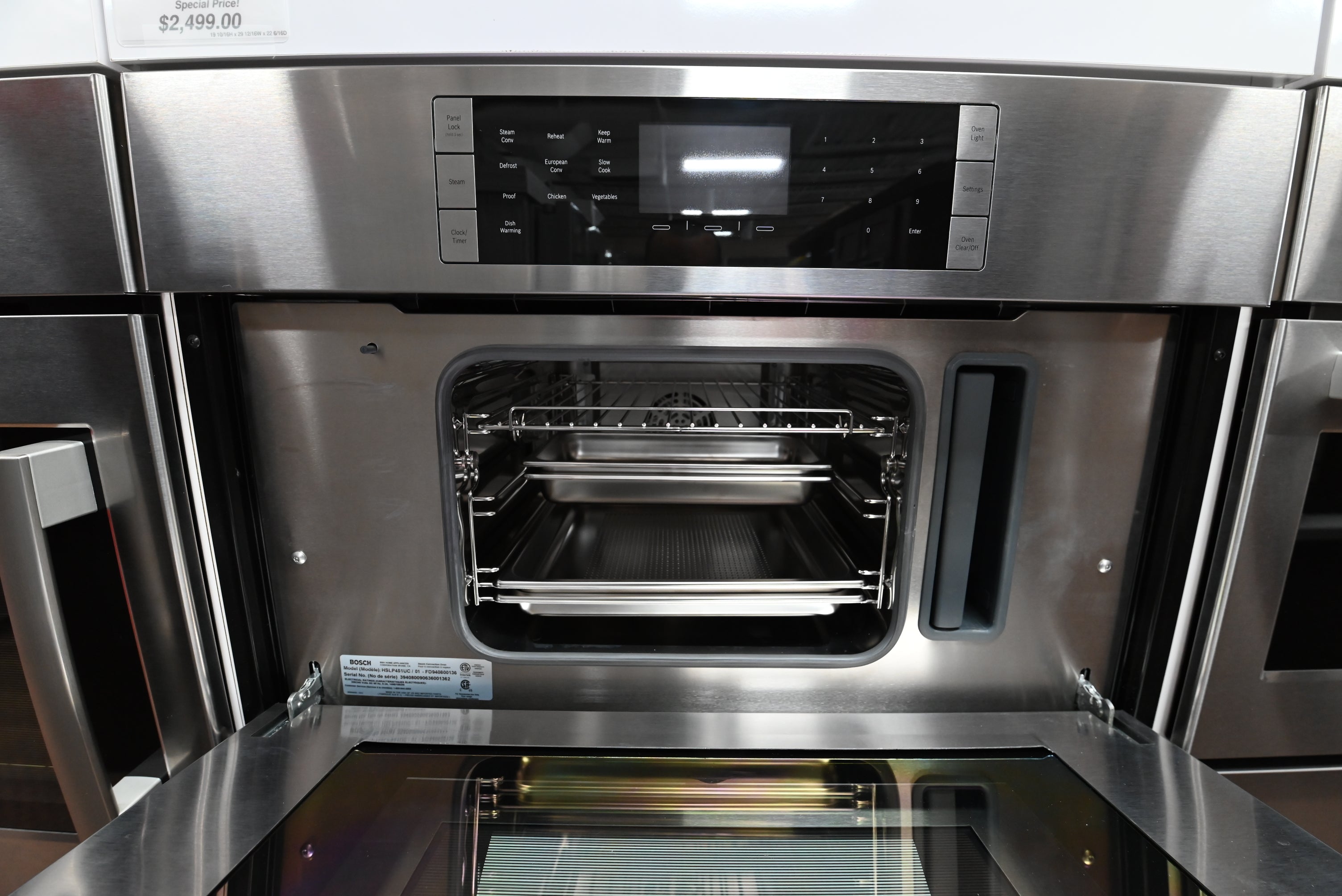 Luxury 30 inch integrated steam oven open showing stainless steel pans and water tank cavity