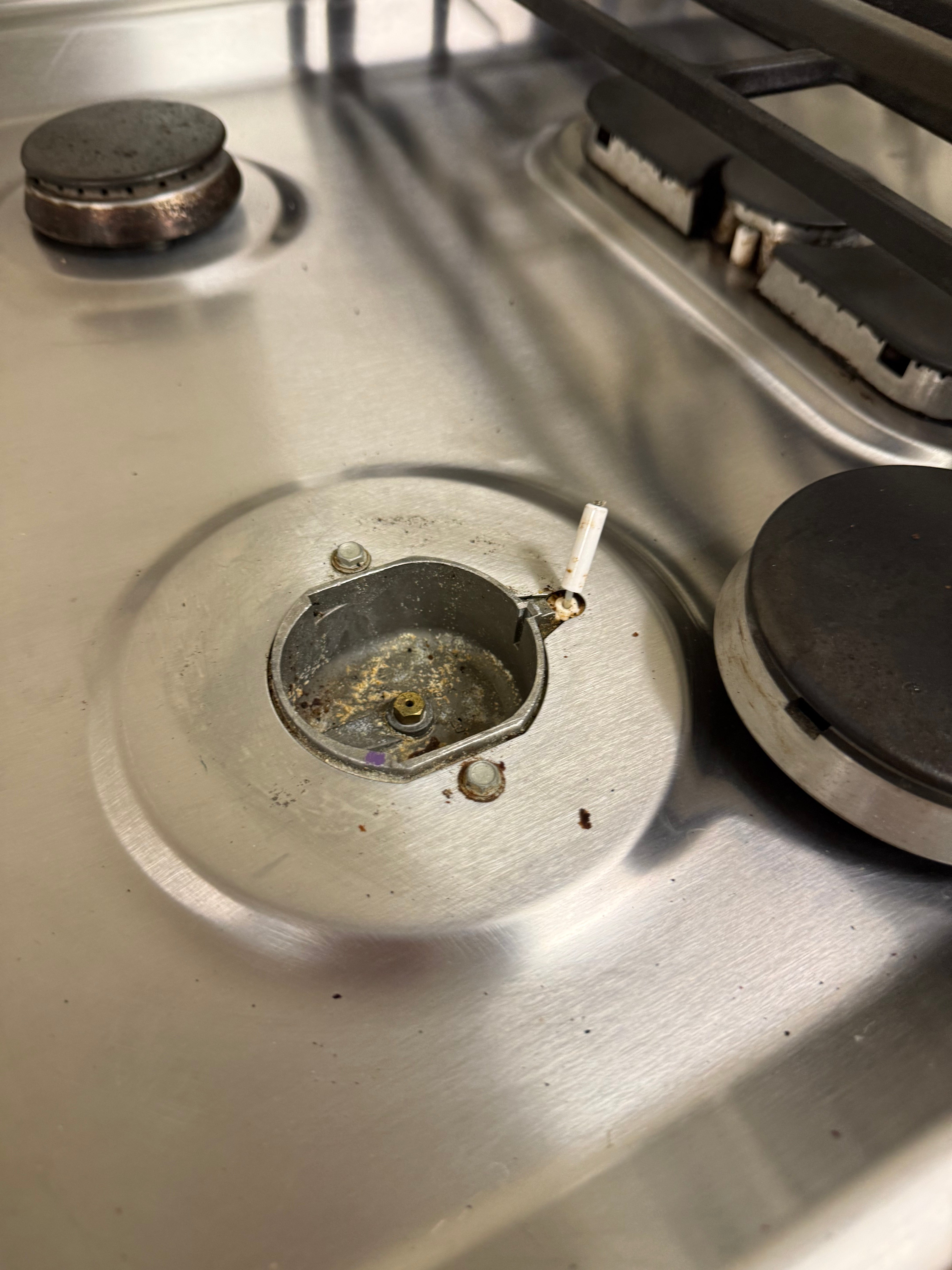 Stove burner with a lit match on a metallic surface