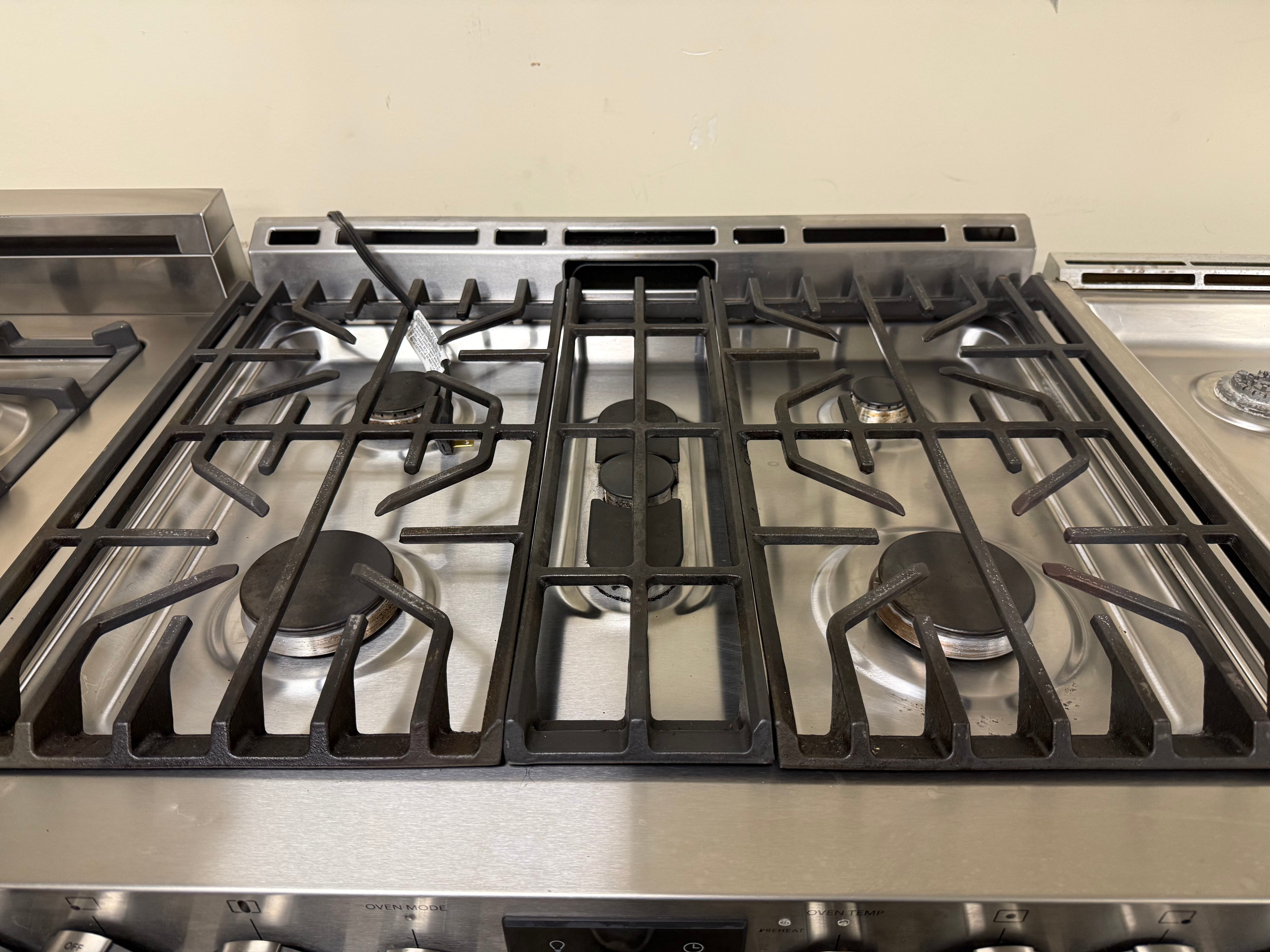 Stainless steel gas stove with black grates on a beige wall background