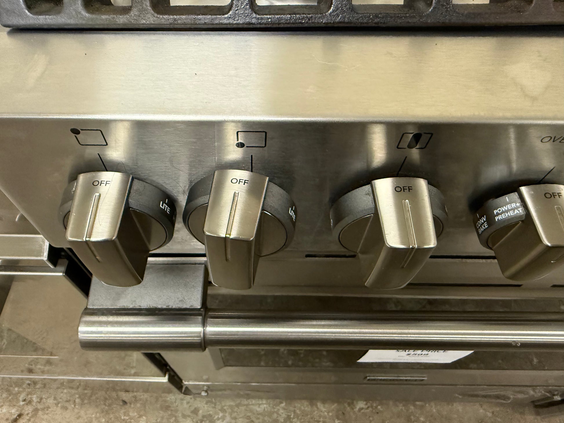Stainless steel stove with four control knobs on a gray background