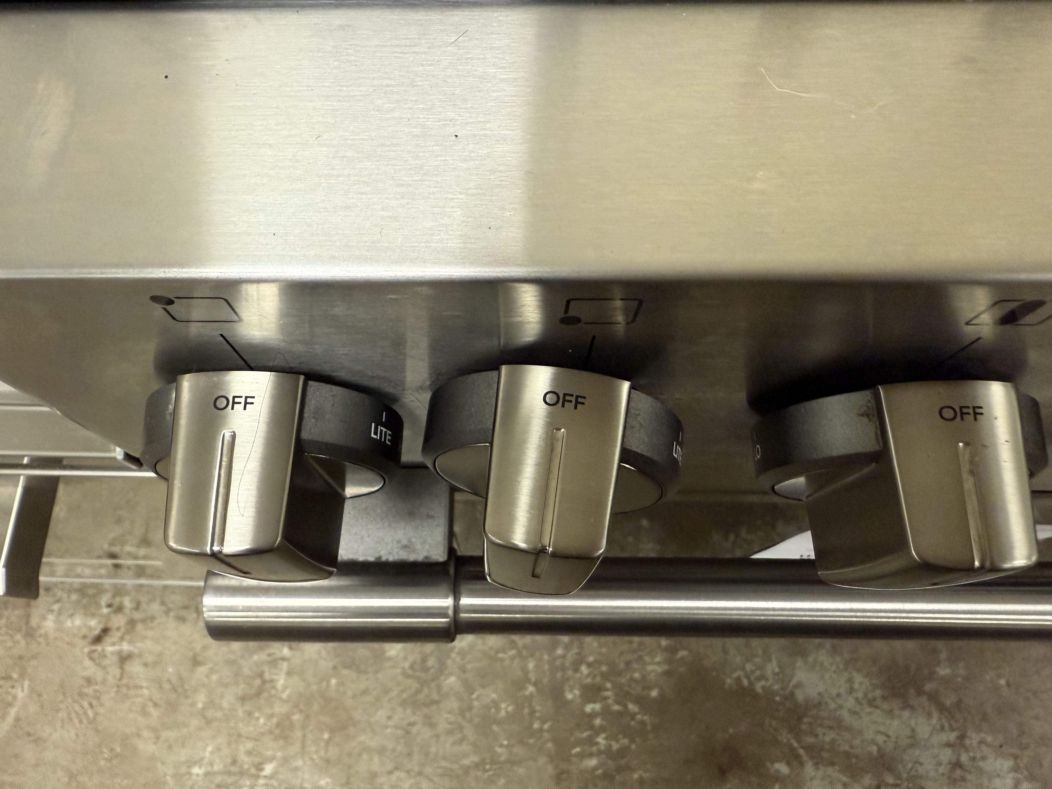 Close-up of three gas stove knobs on a metallic surface