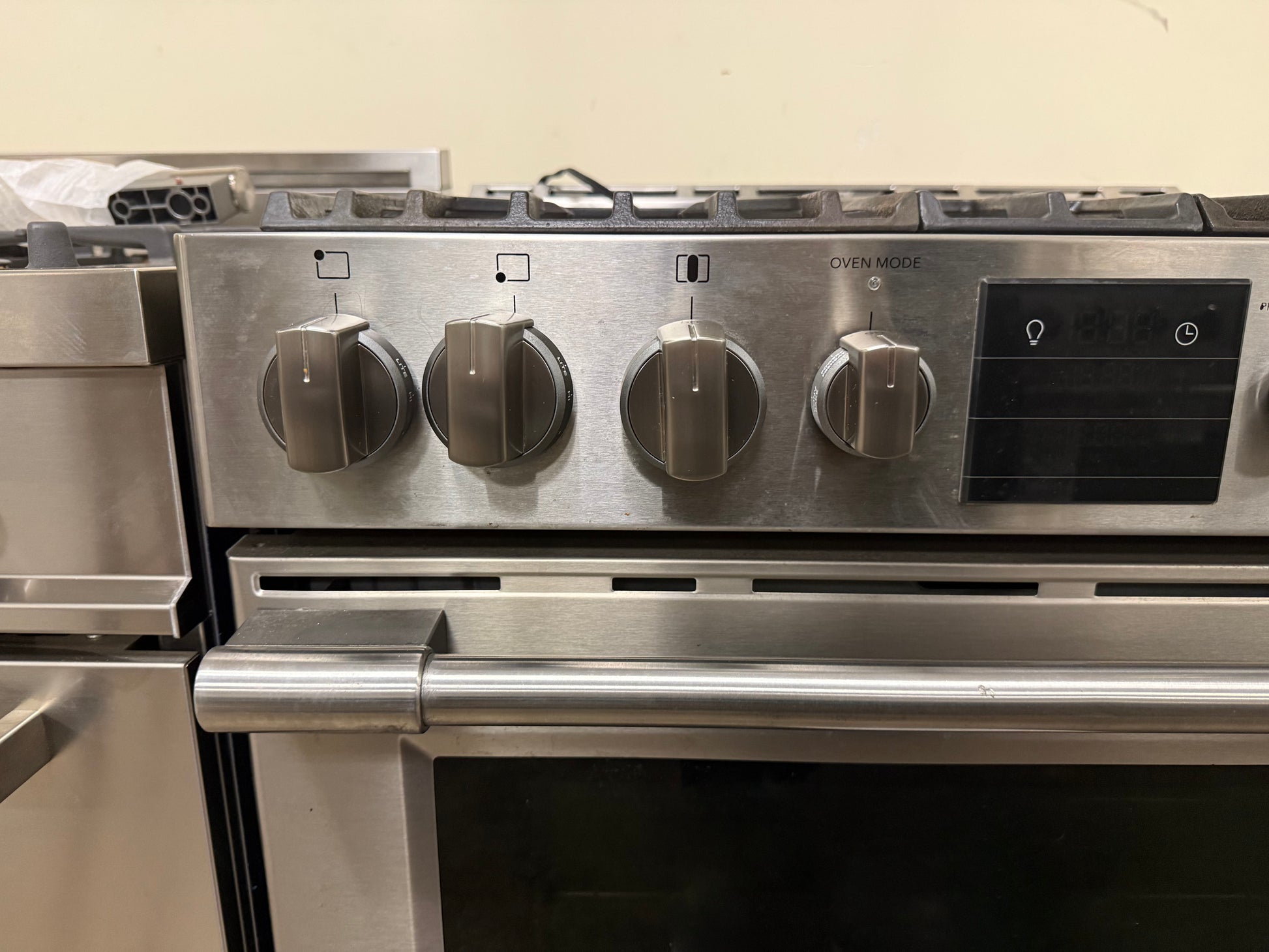 Stainless steel oven with control knobs on a beige wall background