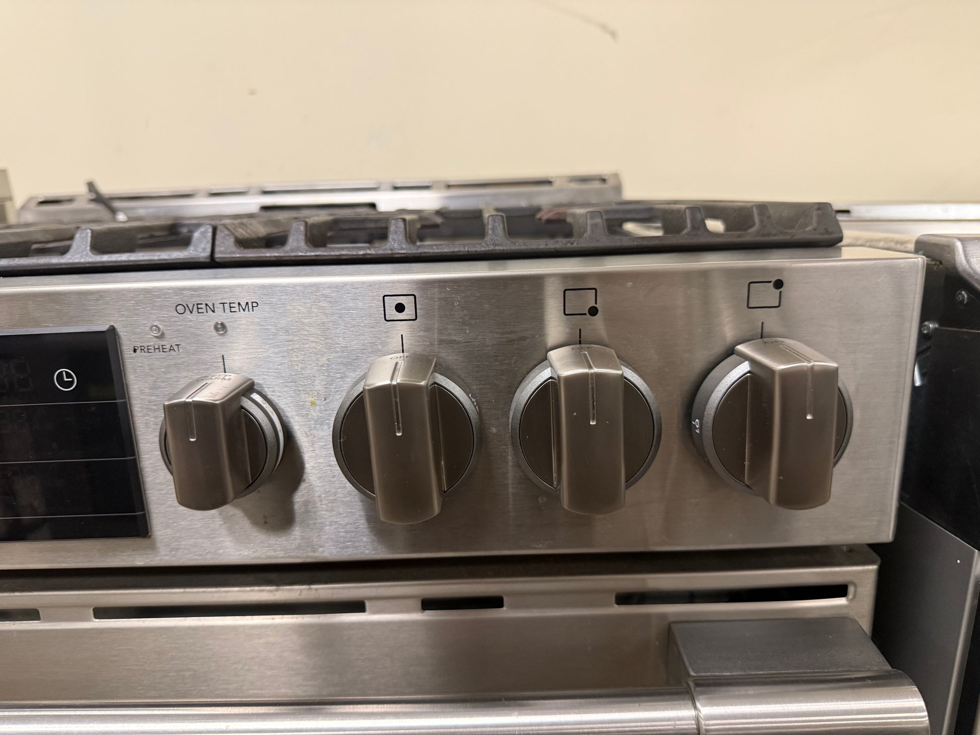 Stainless steel gas range with control knobs on a beige background