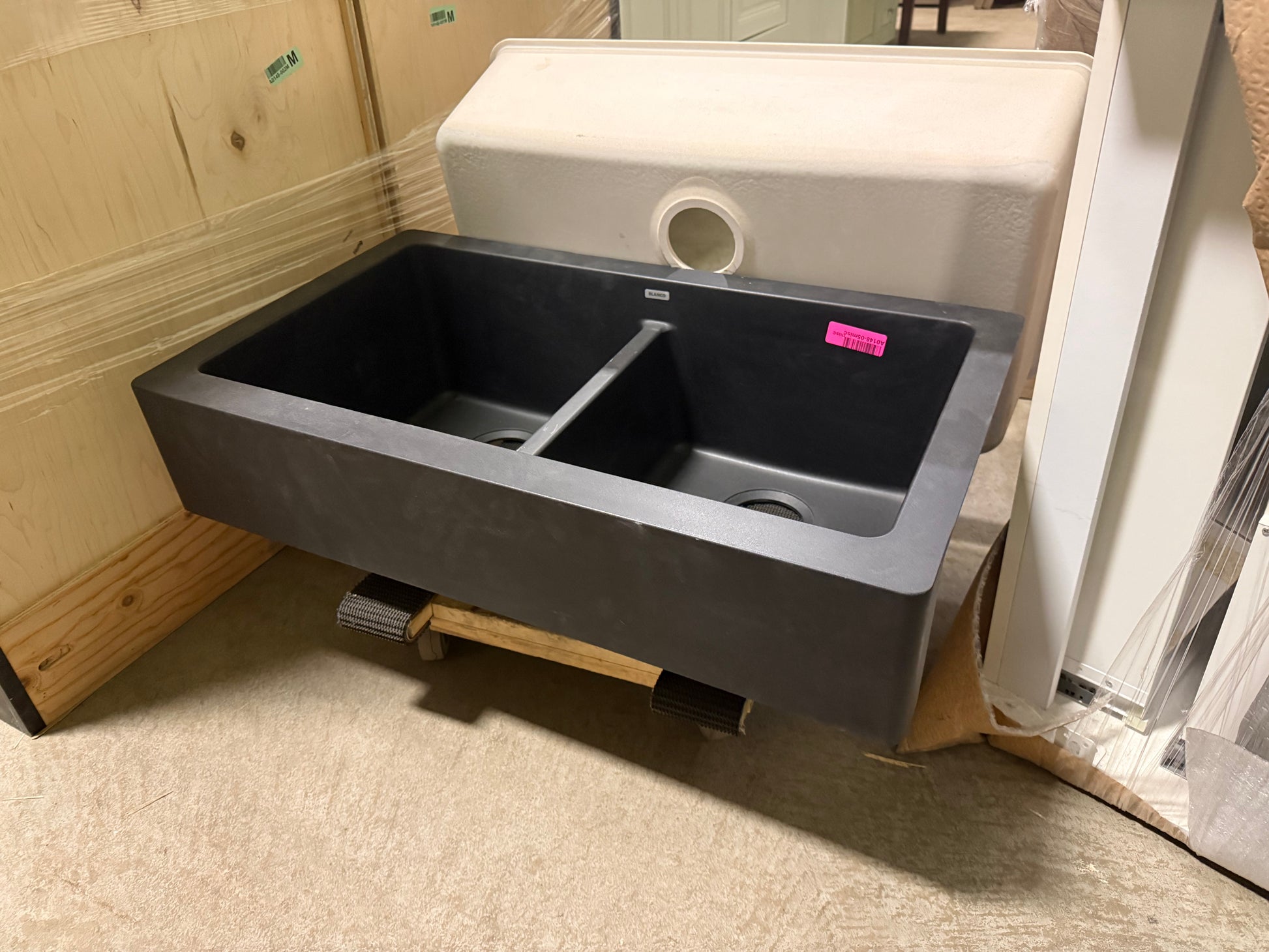 Black kitchen sink with silver faucet on a wooden floor