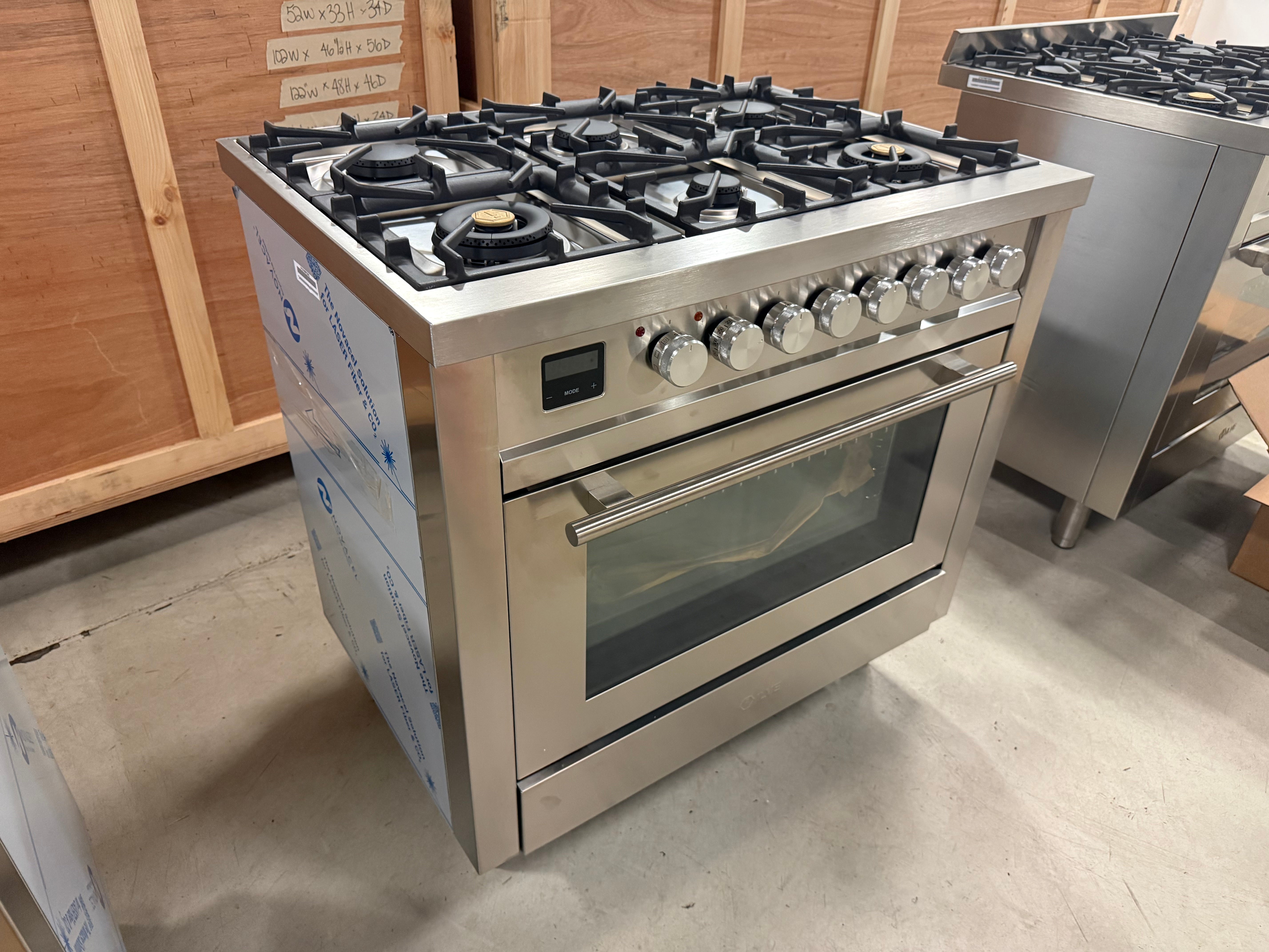 Showroom display ILVE 36 range displaying matte black brass burners and continuous iron grates