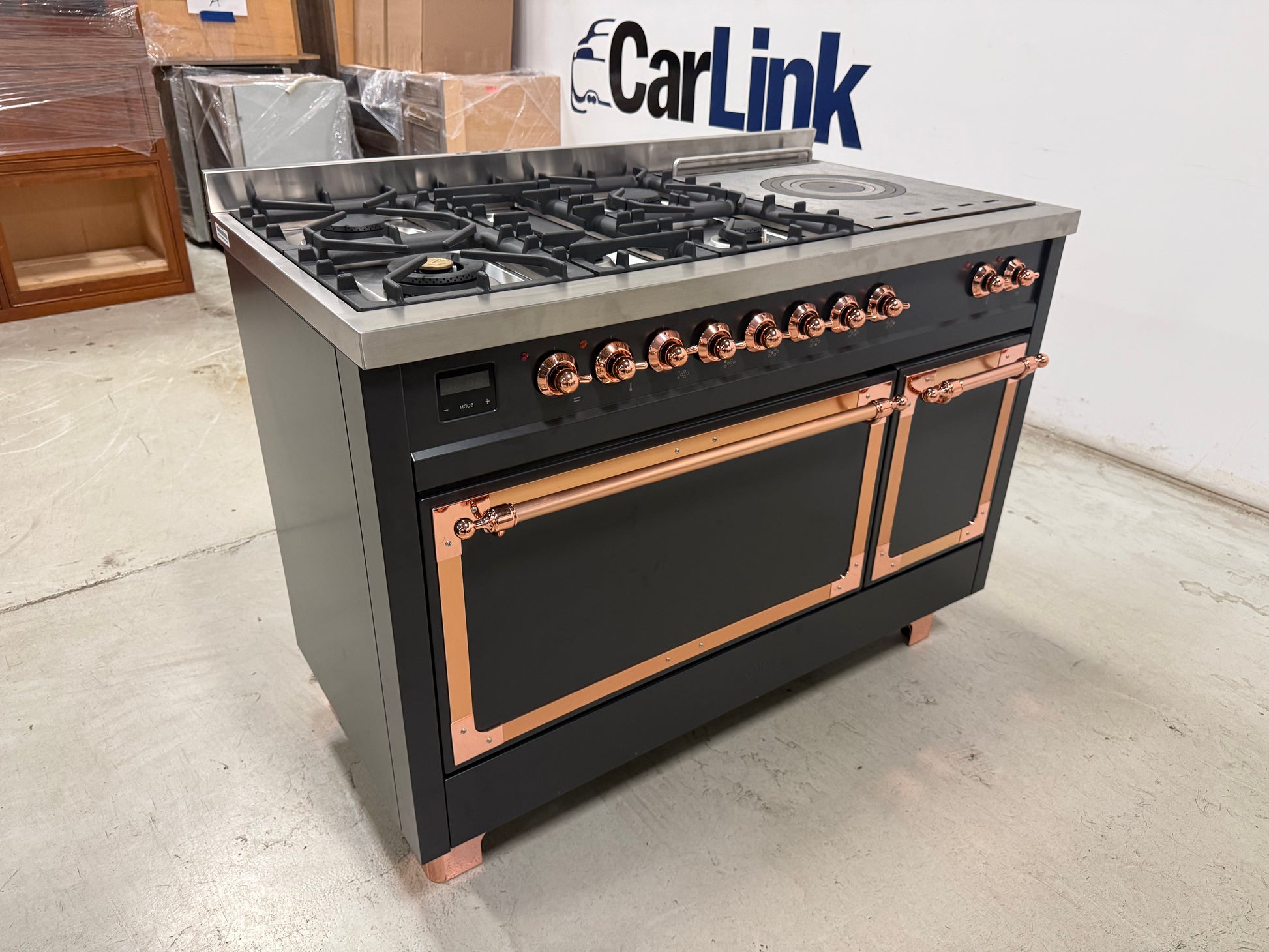 Showroom display 48 inch ILVE range displaying 5 black brass burners and continuous cast iron grates