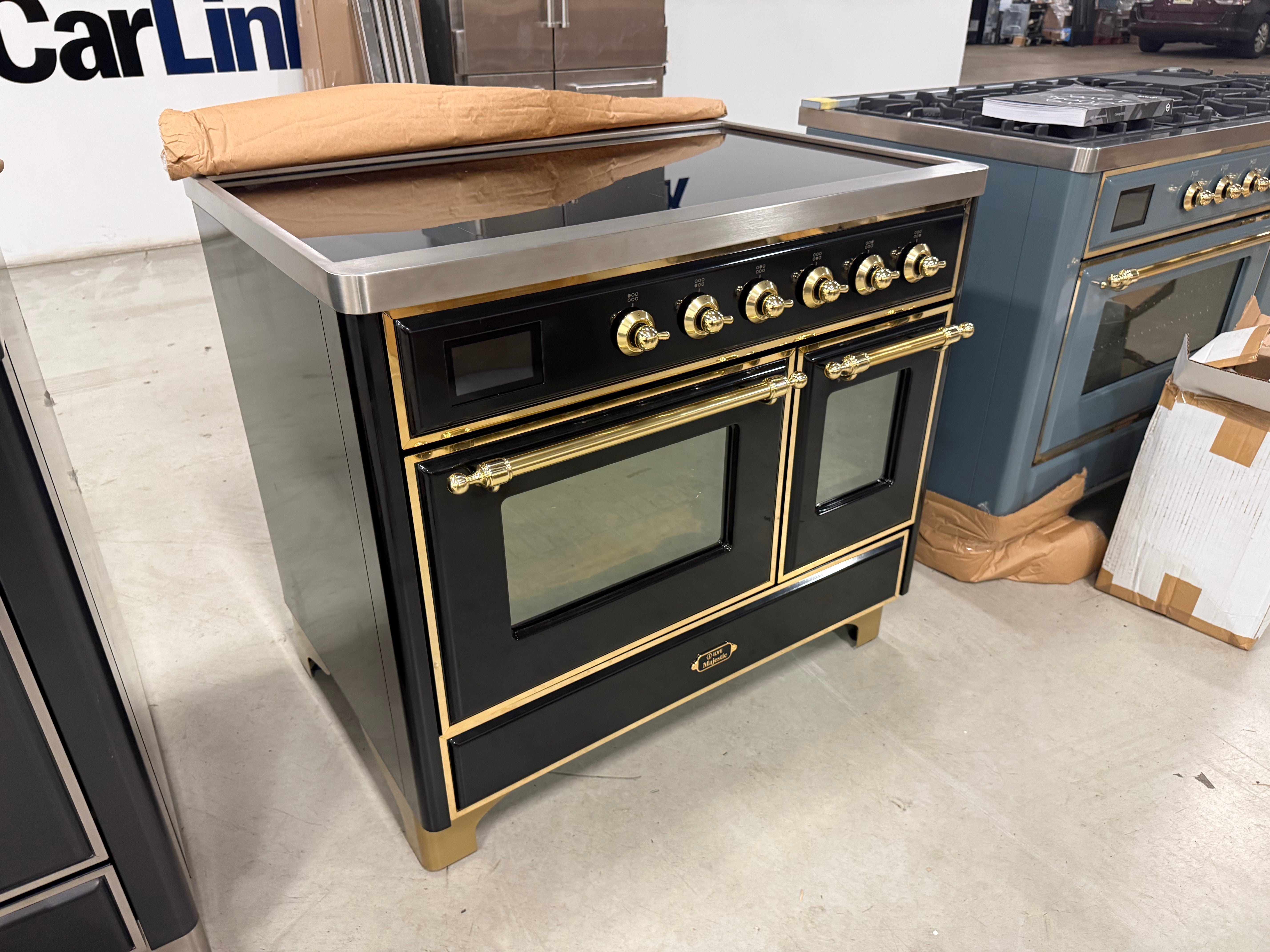 Showroom display 40 inch ILVE electric range showing 6 element glass induction top and brass accents