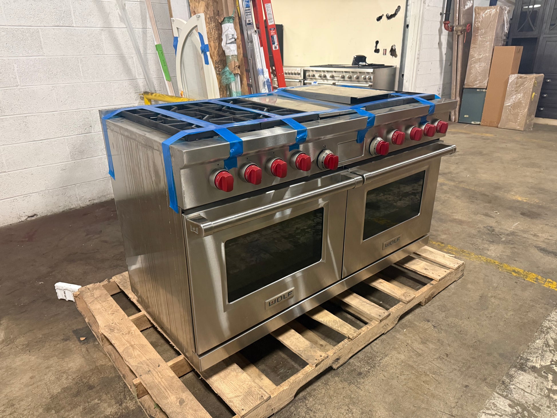 Pre owned Wolf 60 inch pro range twin oven doors open showing cobalt blue porcelain interior and VertiCross convection fans