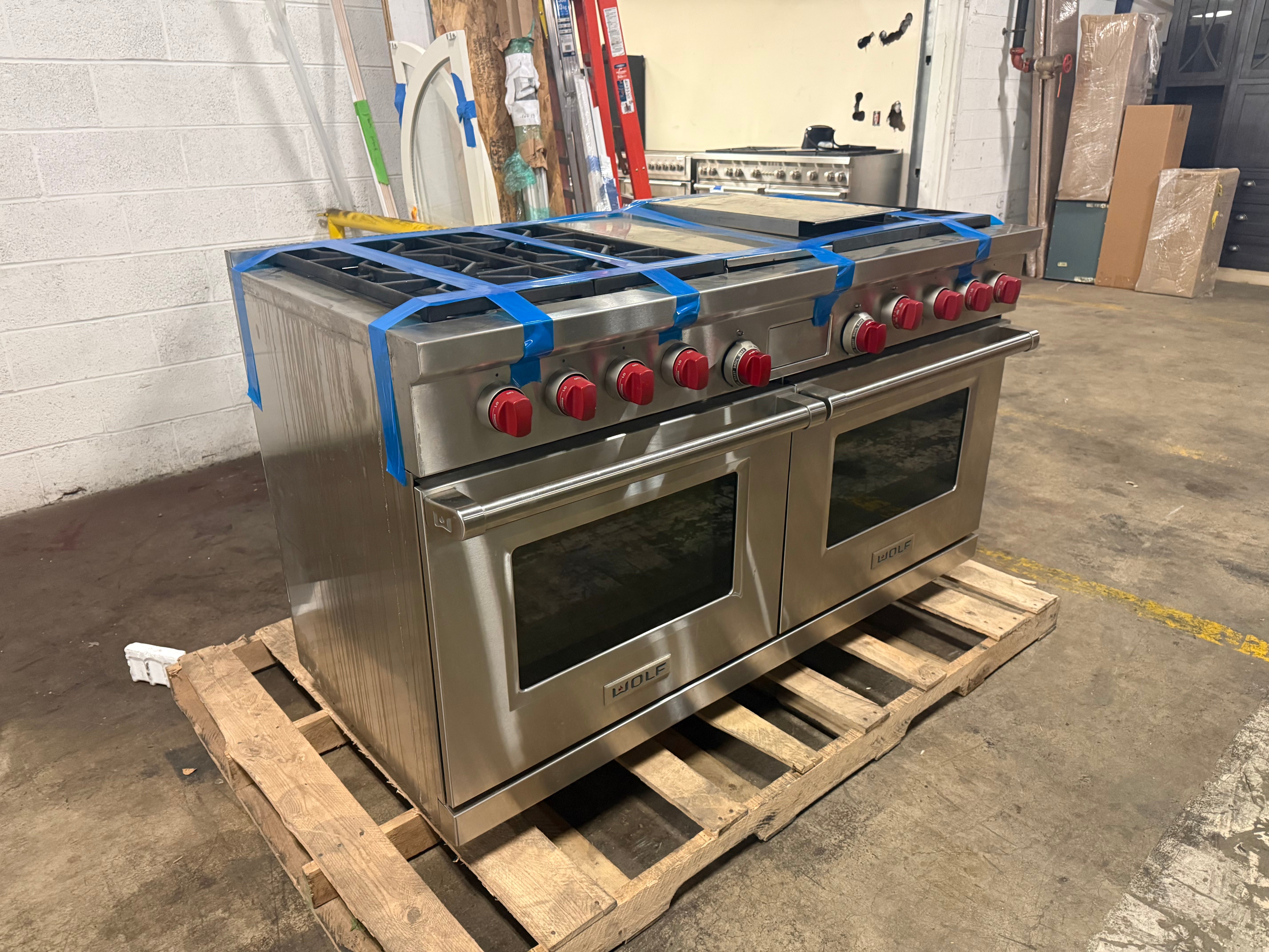 Pre owned Wolf 60 inch pro range twin oven doors open showing cobalt blue porcelain interior and VertiCross convection fans