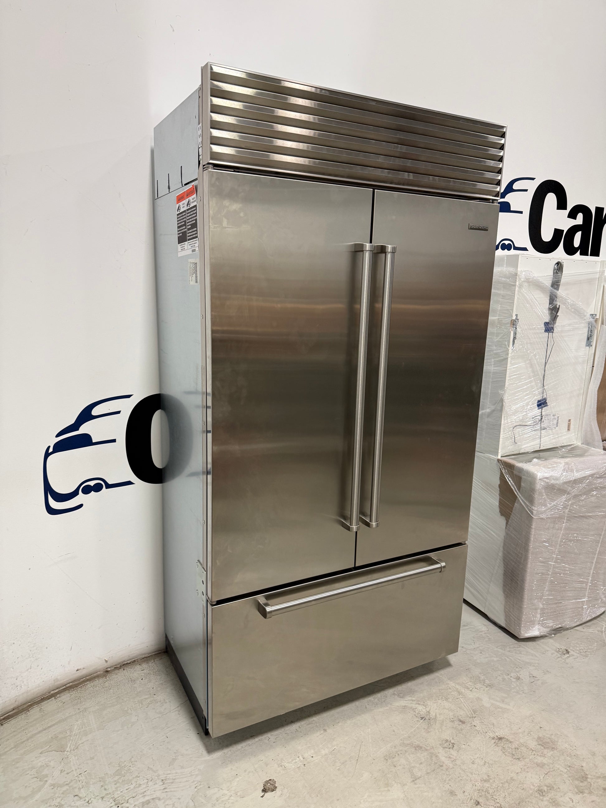Showroom display Sub-Zero 42 fridge displaying split column glass shelves and internal dispenser