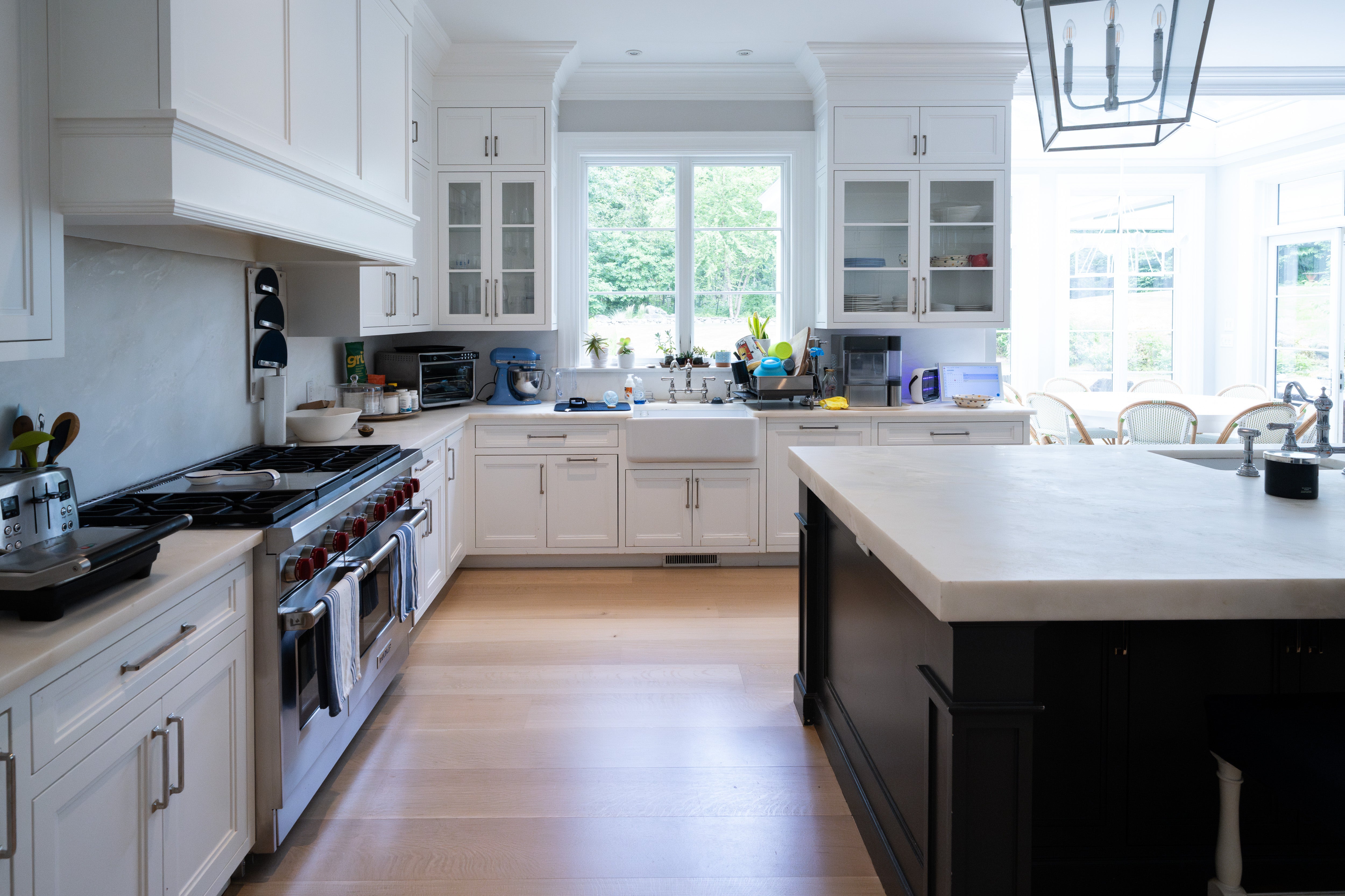 Luxury estate white kitchen layout highlighting professional dual oven Wolf range with red knobs