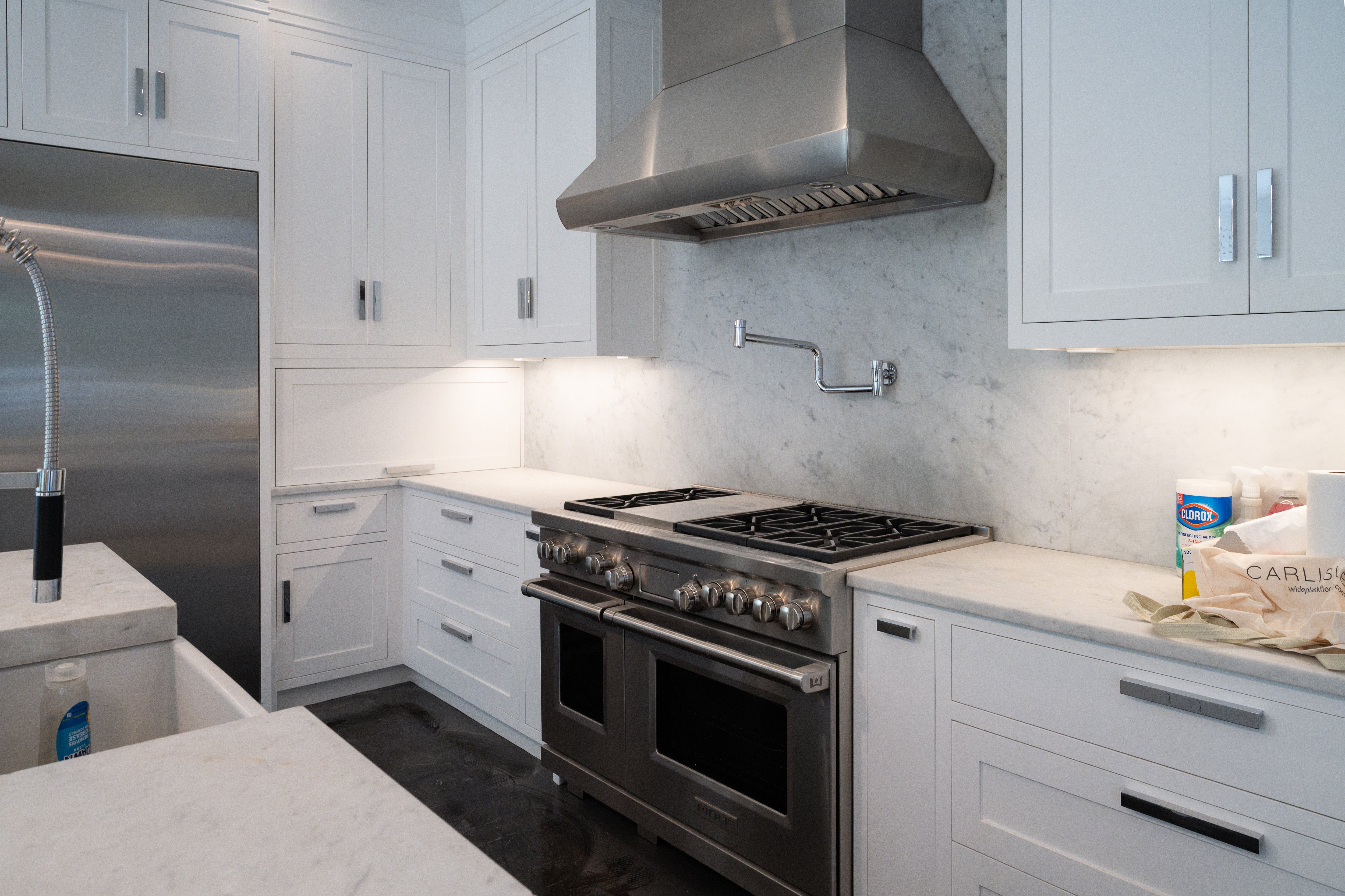 The Pembroke transitional white custom kitchen with shaker cabinets and large central island featuring professional Wolf dual fuel range
