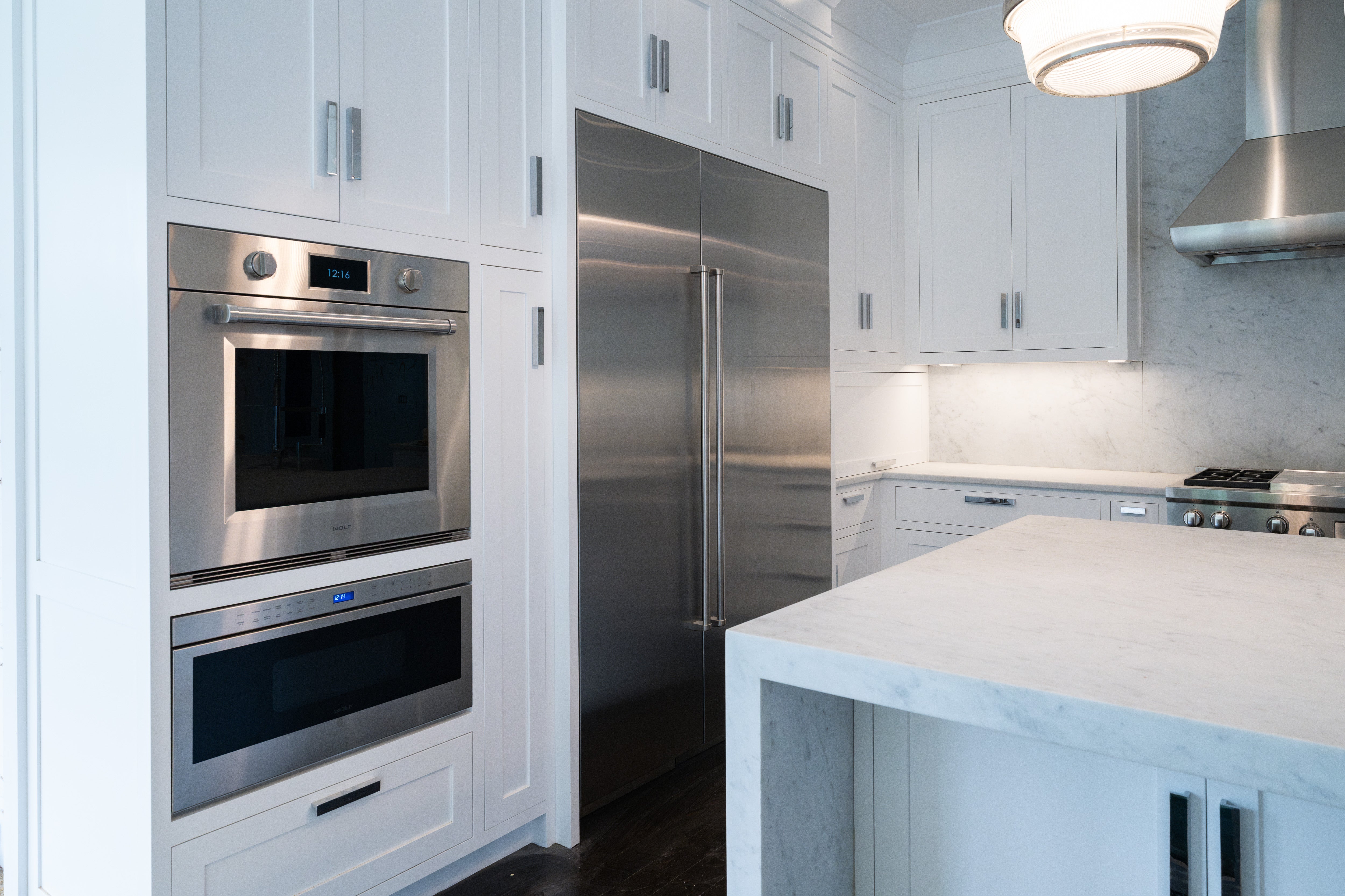 Open view of paneled Sub Zero refrigerator integrated flush with soft white transitional shaker cabinets