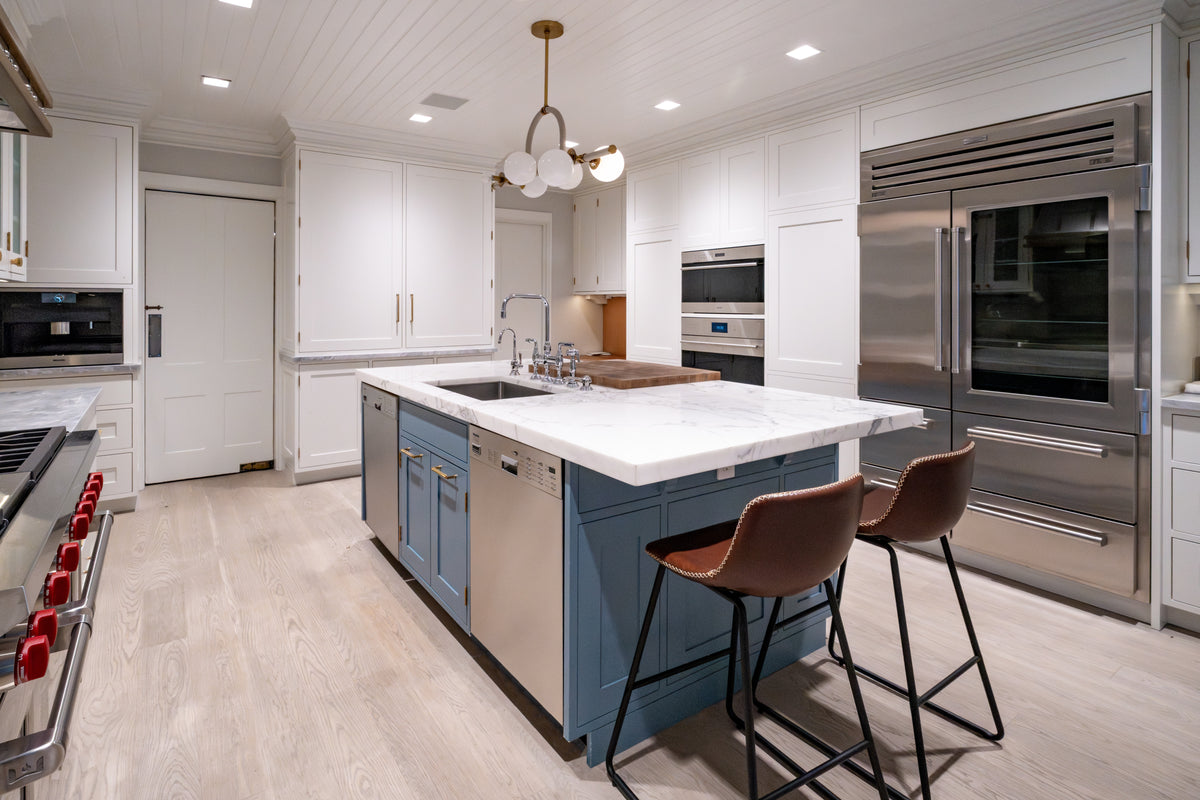 Modern open-concept kitchen island with a calacatta quartz countertop and undermount sink looking toward transitional white cabinetry