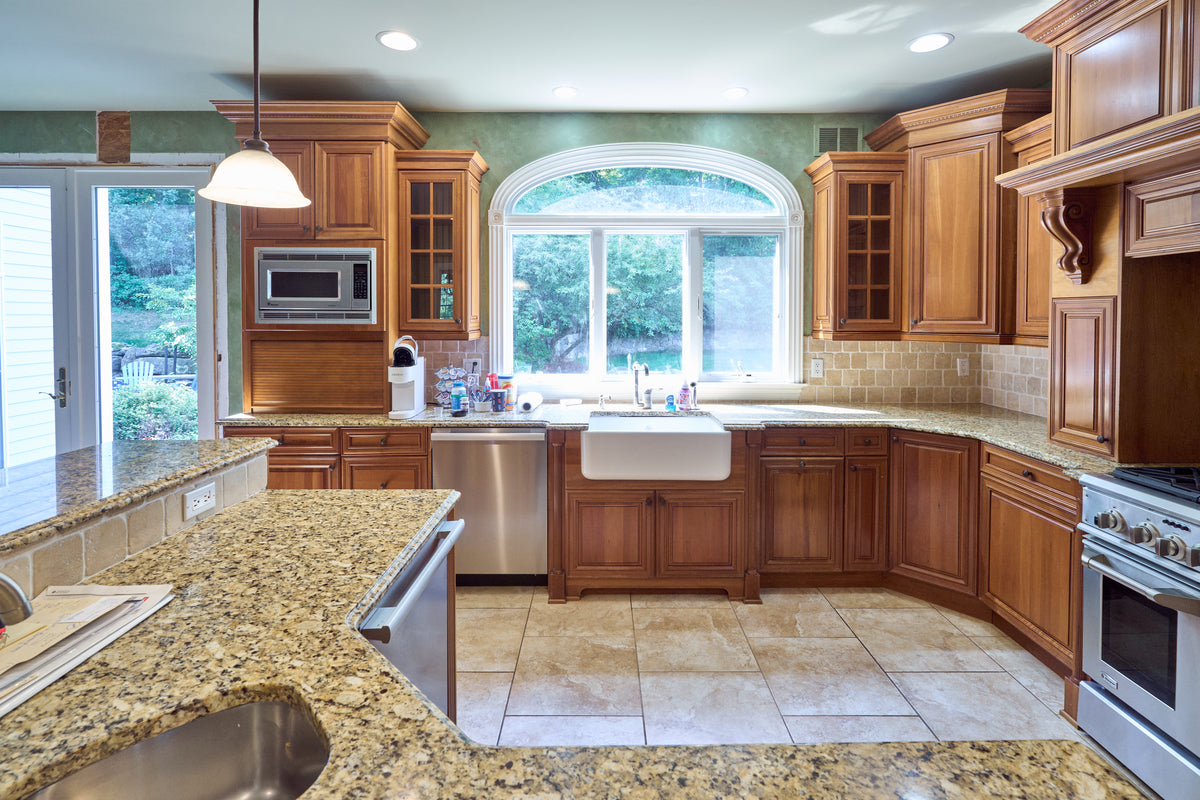 Aurora Circ traditional wooden kitchen with raised panel cabinets granite island farmhouse sink built in microwave and stainless steel range