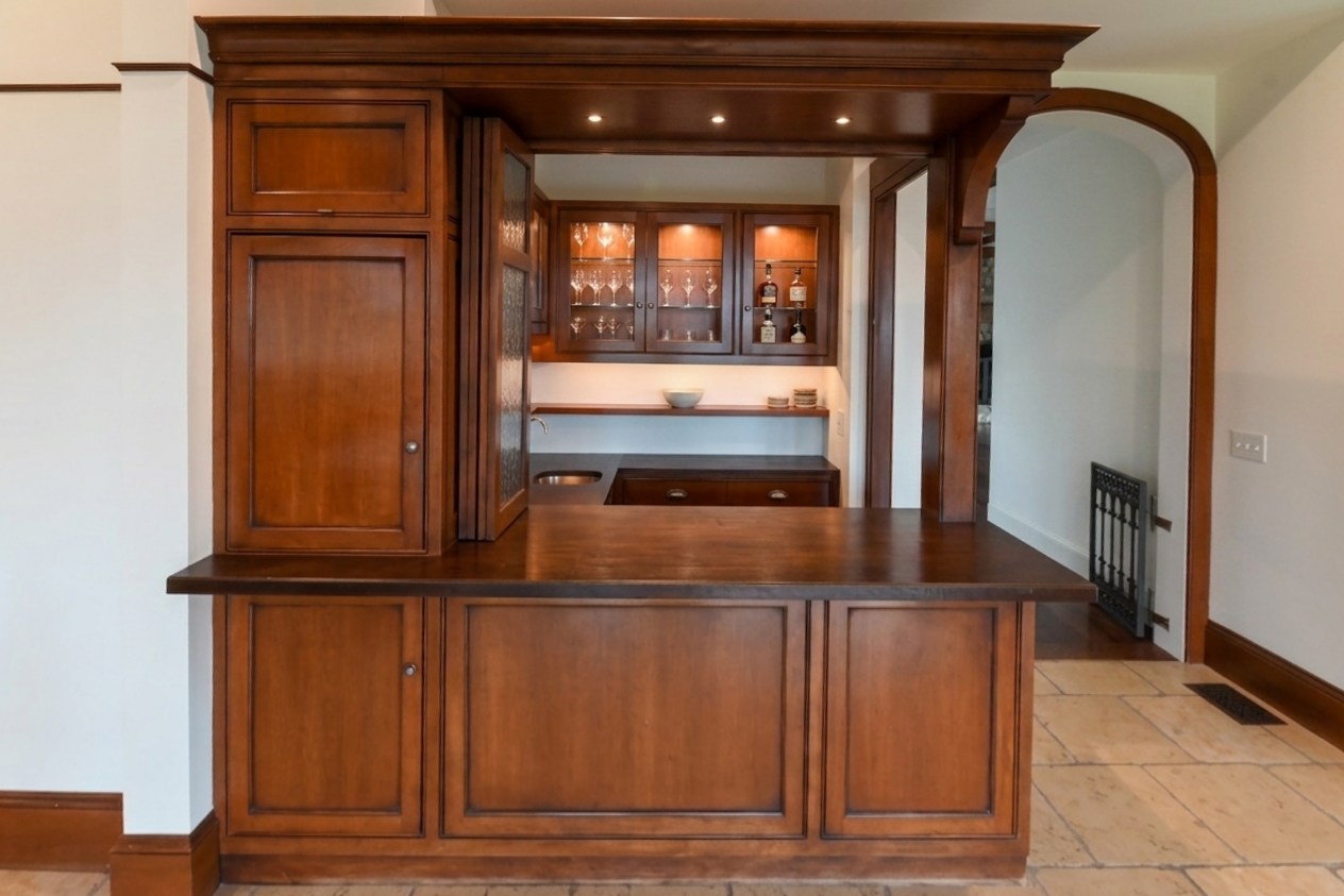 Custom traditional dark wood wet bar with integrated wine cooler and sink