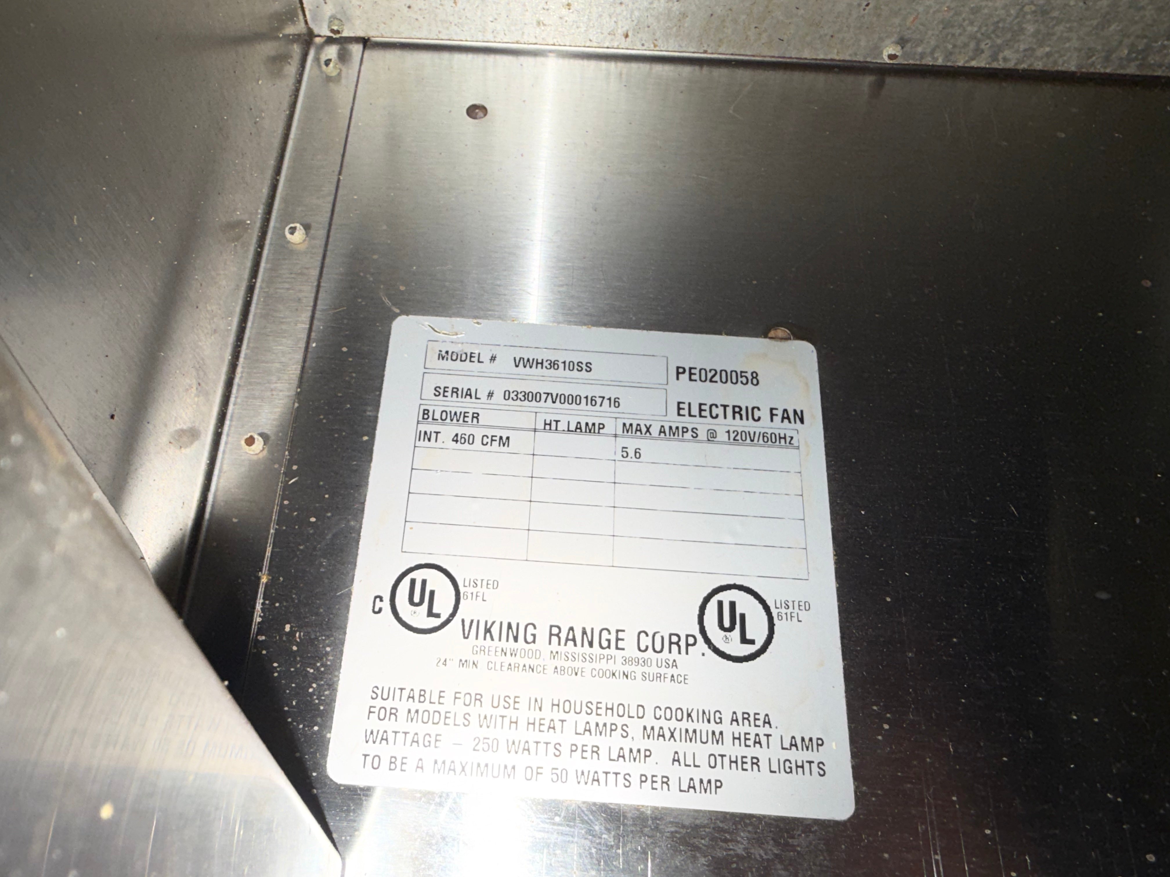 A close-up of a metal appliance interior showing a white product information label with printed text and UL logos. The label includes Viking Range Corp branding and model details for an electric fan.