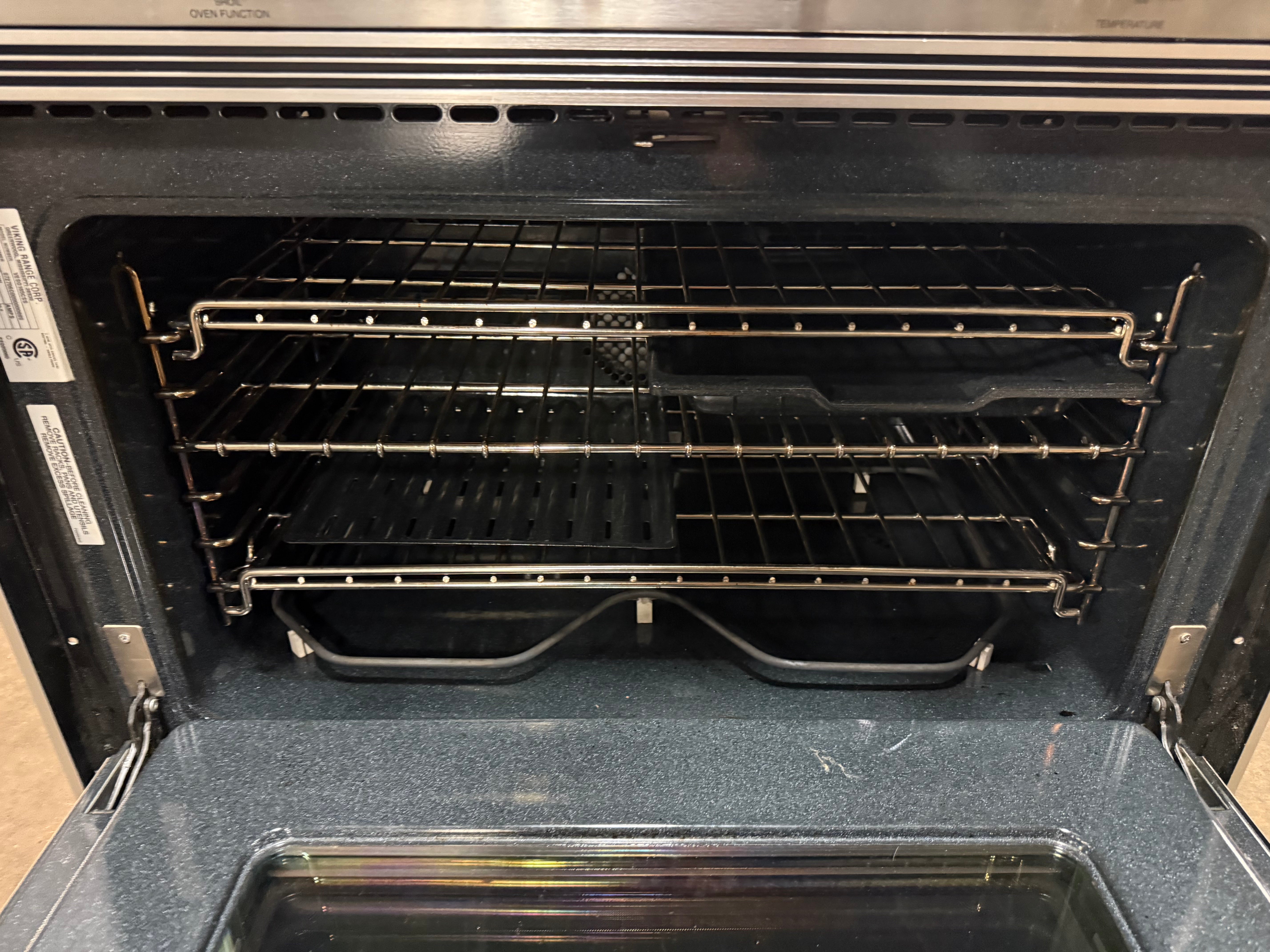 An open black oven with three metal racks and a glass door, photographed from inside the oven looking out.