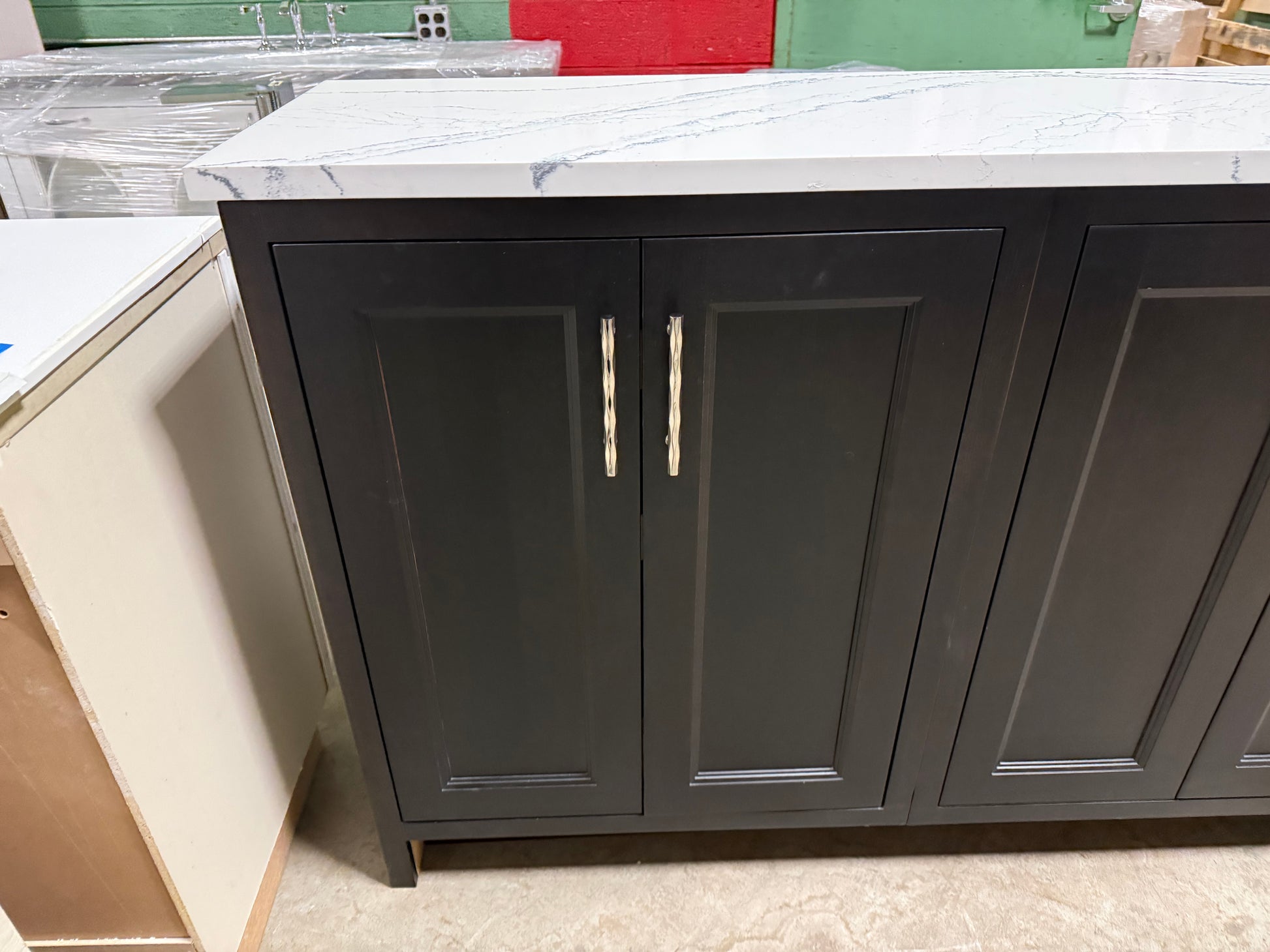 Dark gray cabinet with two doors and silver handles on a tiled floor.