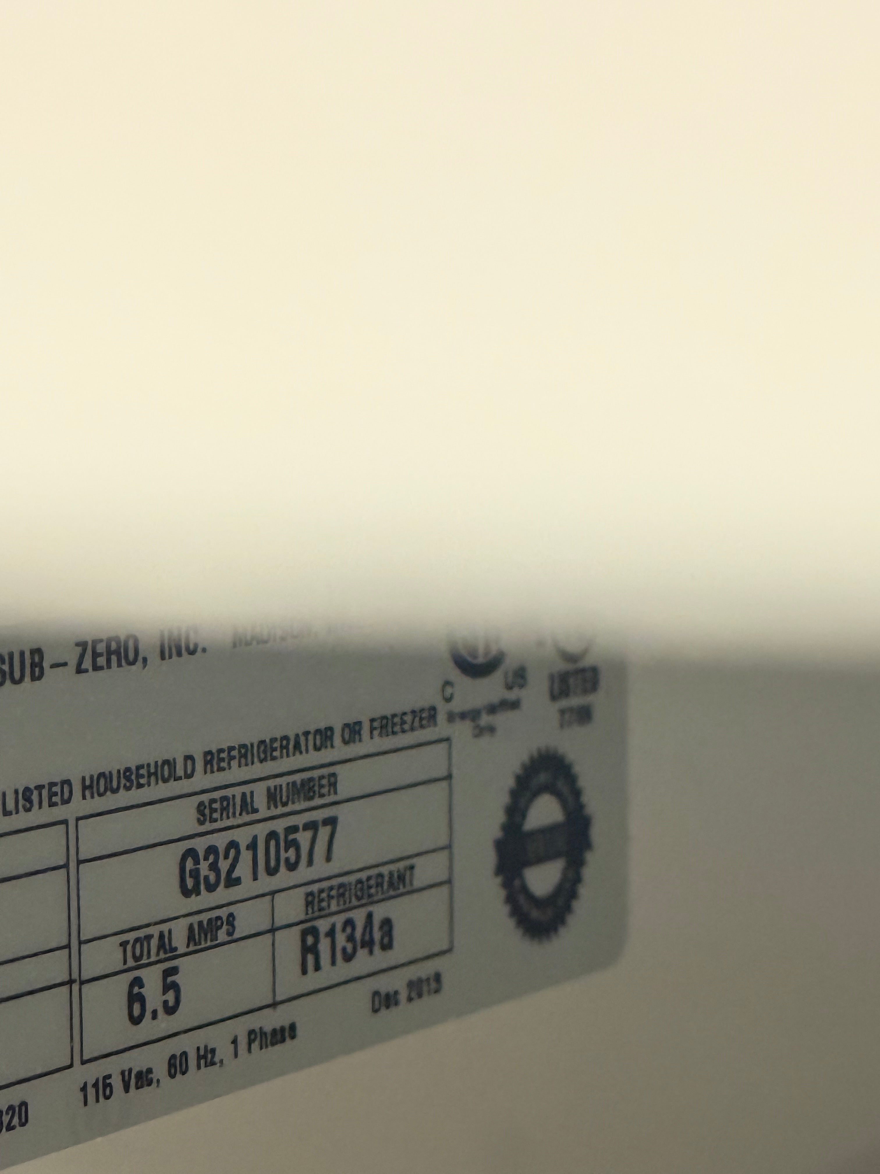 A close-up of a refrigerator or freezer label showing the serial number G3210577, total amp-hours 6.5, and refrigerant R134a, with partial text reading SUB-ZERO, Inc.